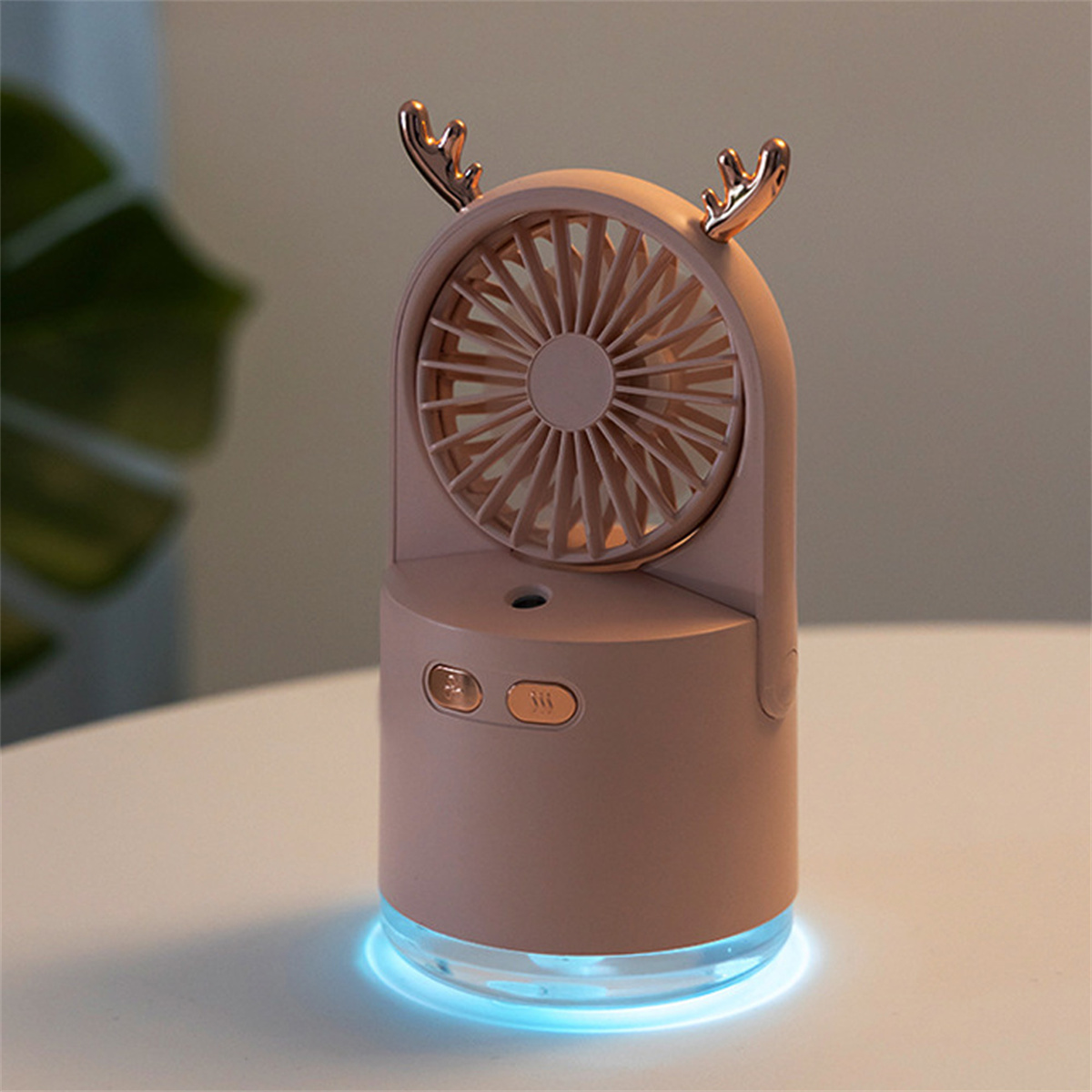 Ein kleiner, rosa Ventilator mit goldenen Geweihen oben. Er hat Knöpfe und ein blaues Licht am Sockel.