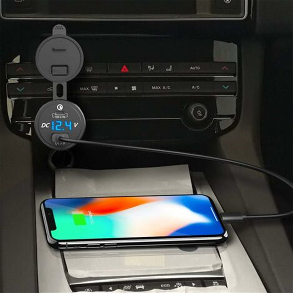 Autoladegerät mit Bildschirm, der 12,4 V anzeigt, an ein ladendes Telefon angeschlossen.