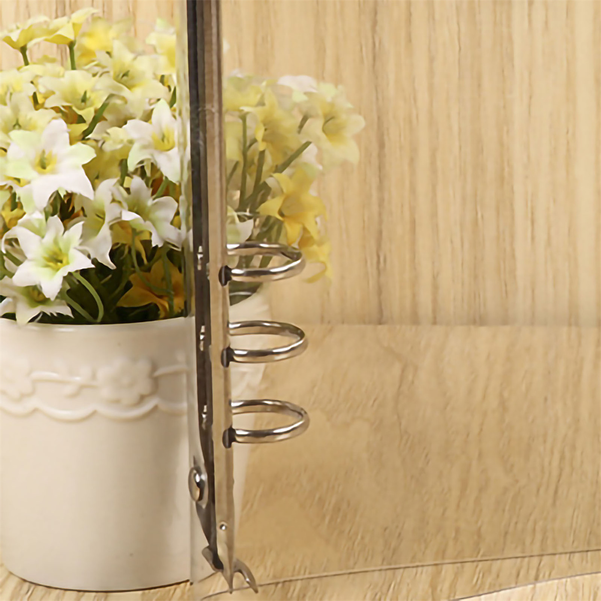 Ein transparenter Ordner mit gelben Blumen vor einem Holzhintergrund.