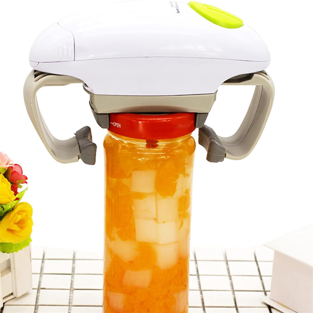 Gläseröffner mit weißem Oberteil und grauen Griffen. Ein Glas wird mit orangenem Inhalt geöffnet.