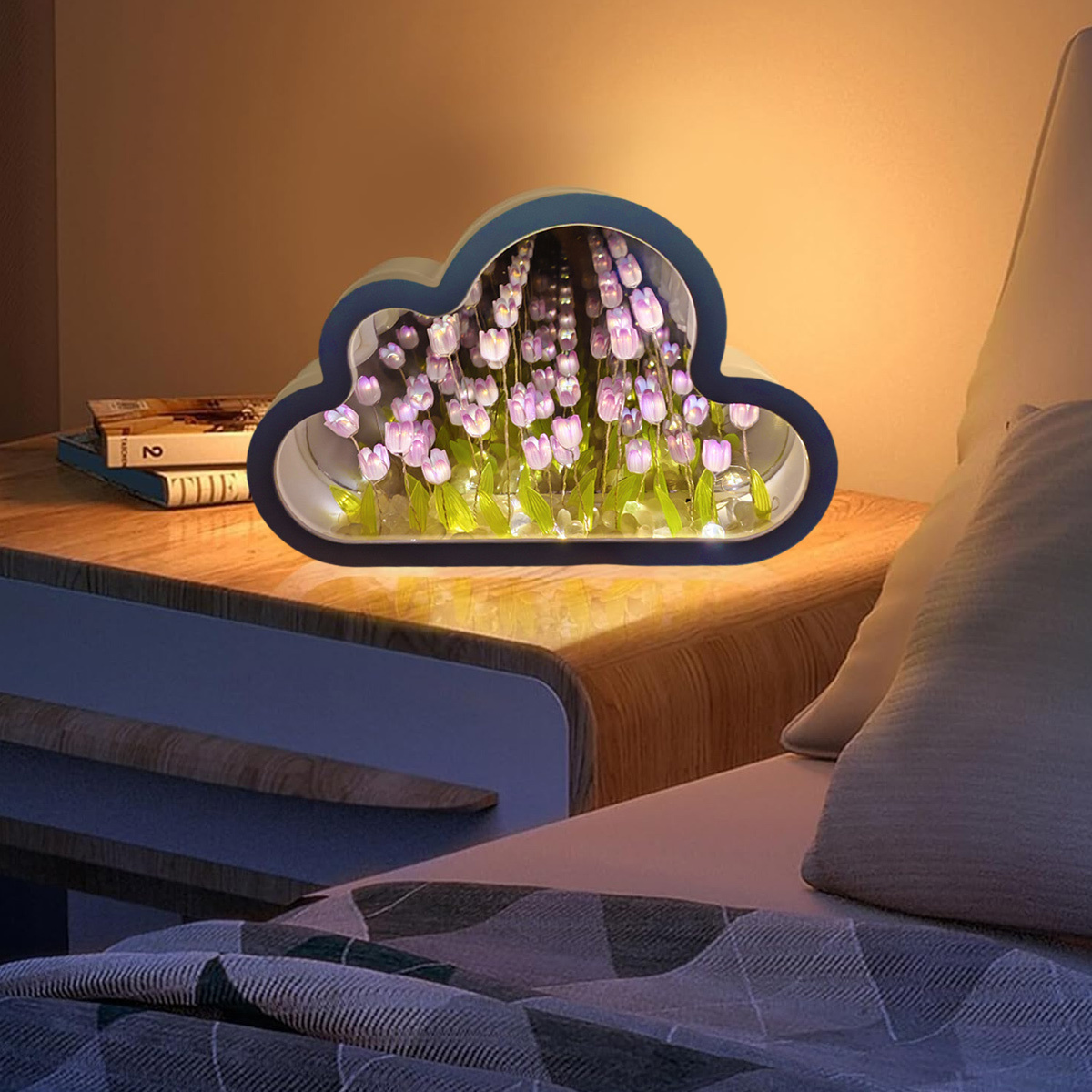 Ein wolkenförmiges Licht mit Blumen darin, das auf einem Nachttisch neben einem Bett steht.
