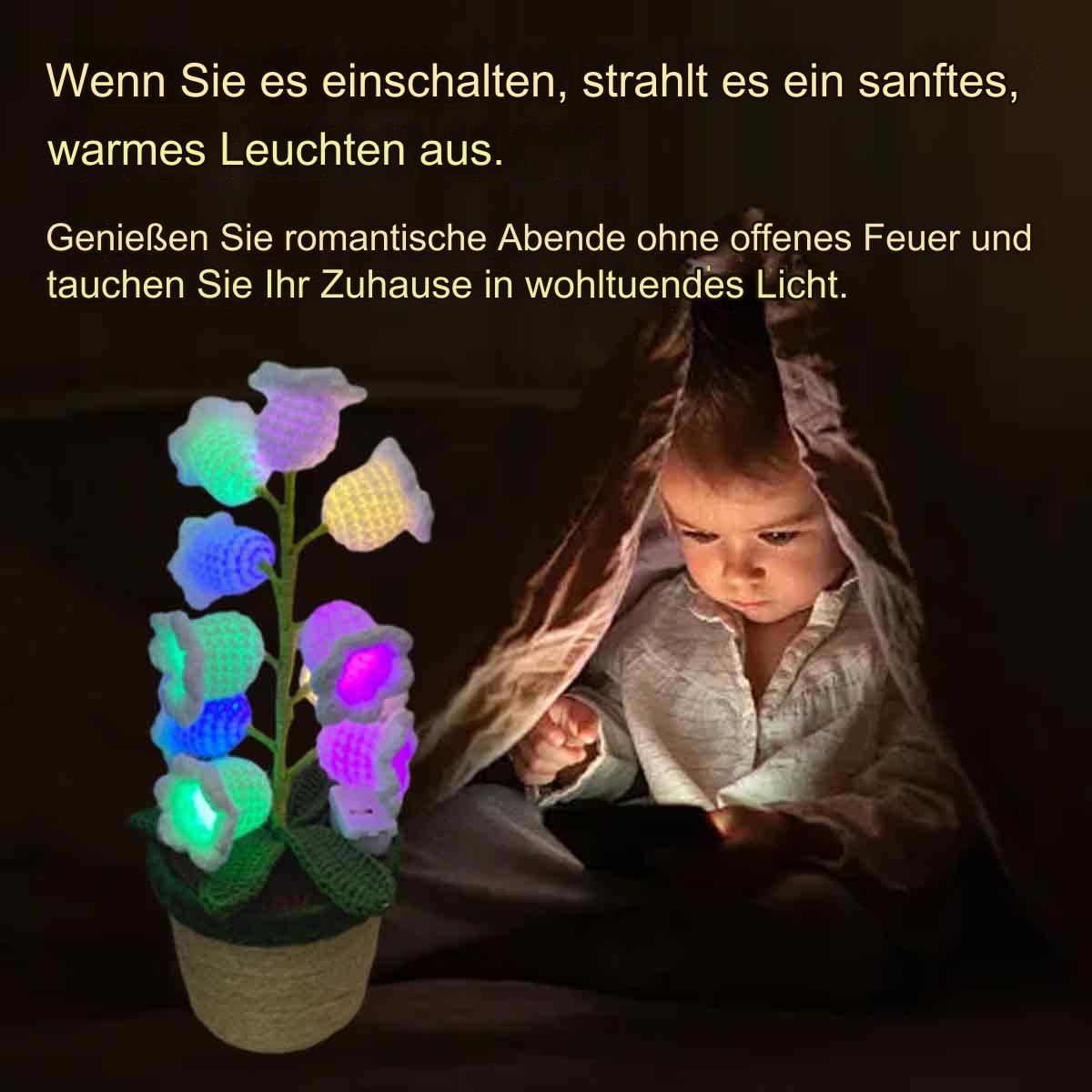 Ein Kind unter einer Decke betrachtet eine leuchtende Blumenlampe.