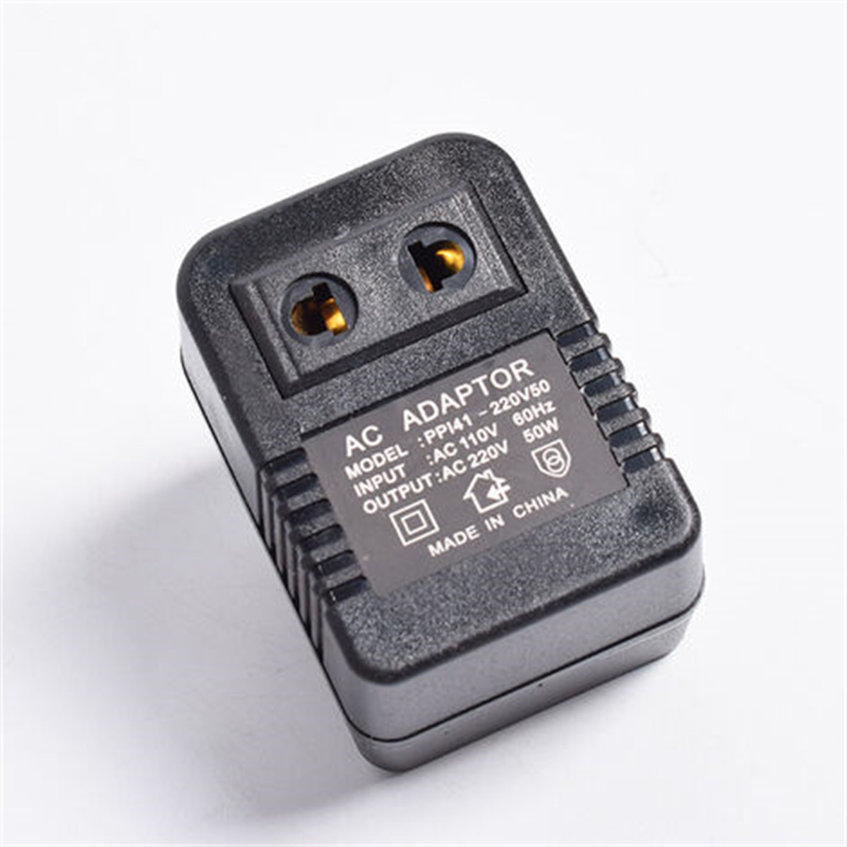 Schwarzer AC-Adapter mit zwei Steckdosen, beschriftet: AC ADAPTOR, mit Eingangs-/Ausgangsdaten und Made in China.