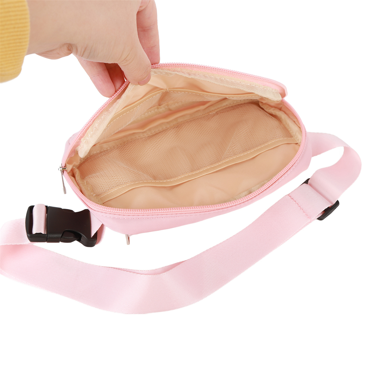 Eine rosa Bauchtasche mit offenem Reißverschluss. Eine Hand greift hinein und zeigt die Innenfächer.