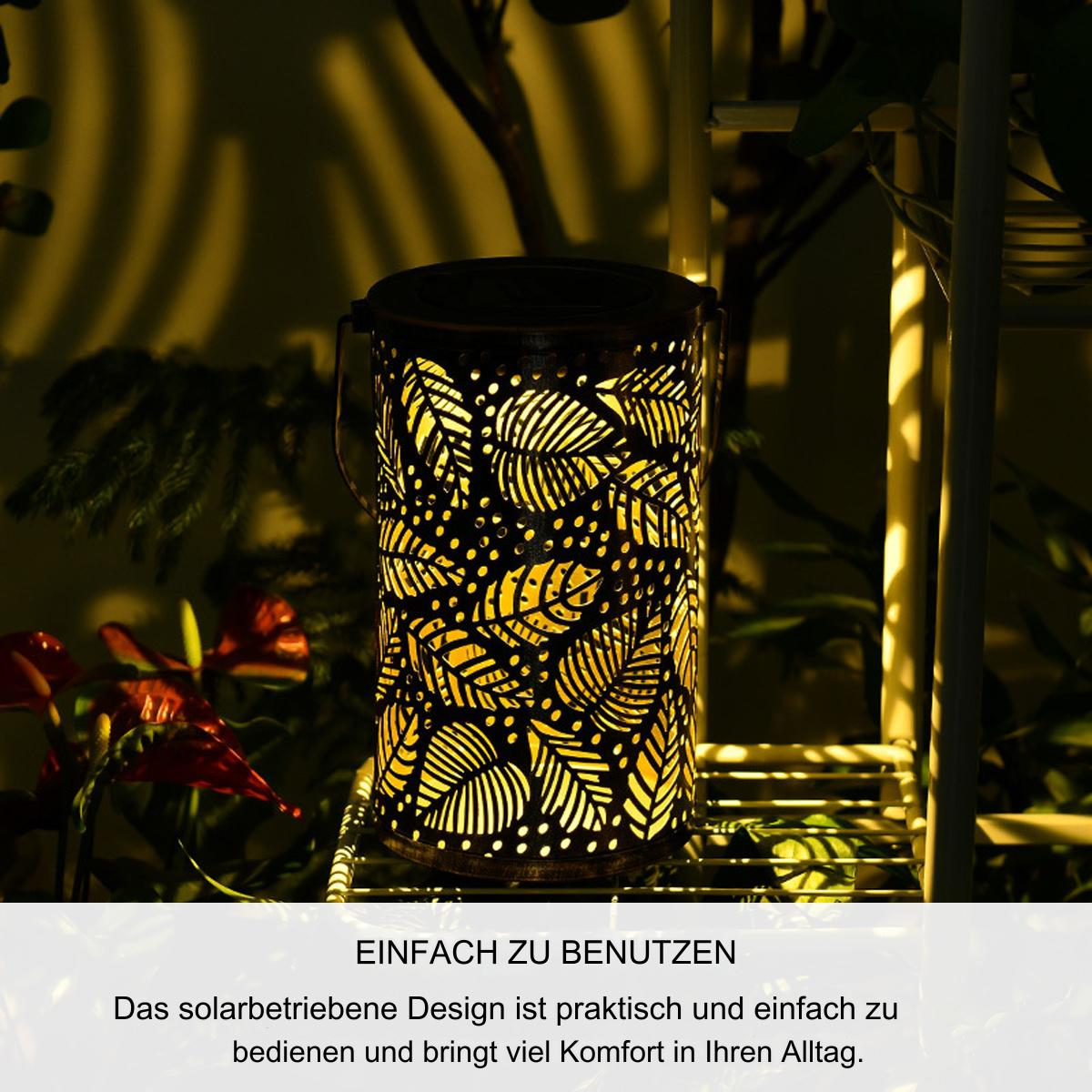 Eine solarbetriebene Laterne mit Blattausschnitten, die Licht aussendet und von Pflanzen umgeben ist.