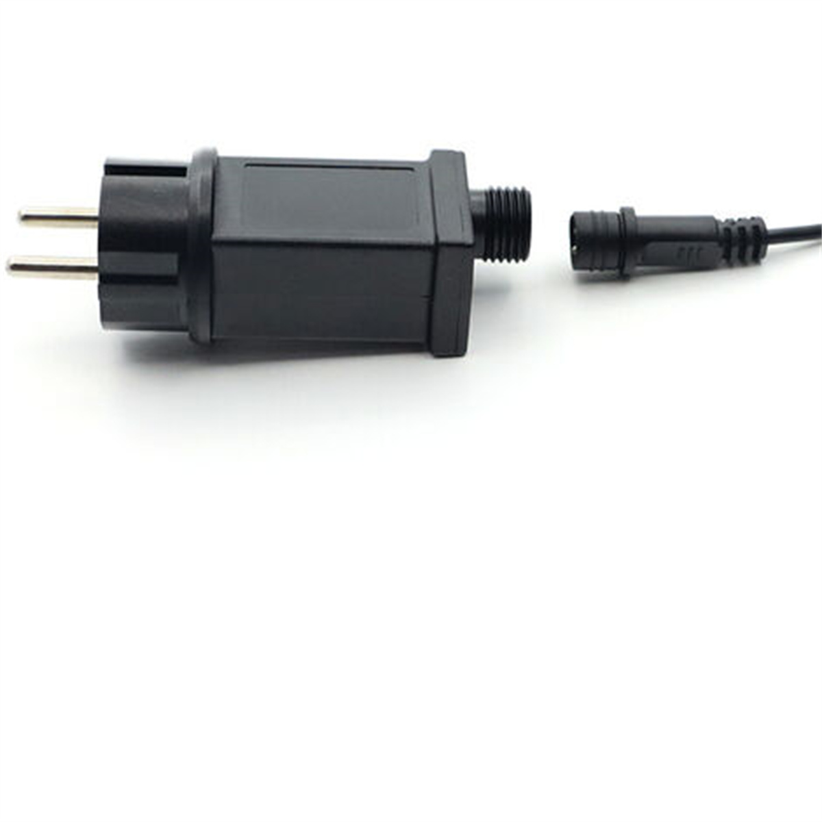 Ein schwarzer Stecker mit zwei Stiften, der mit einer schwarzen Box verbunden ist, und ein separates schwarzes Kabel.