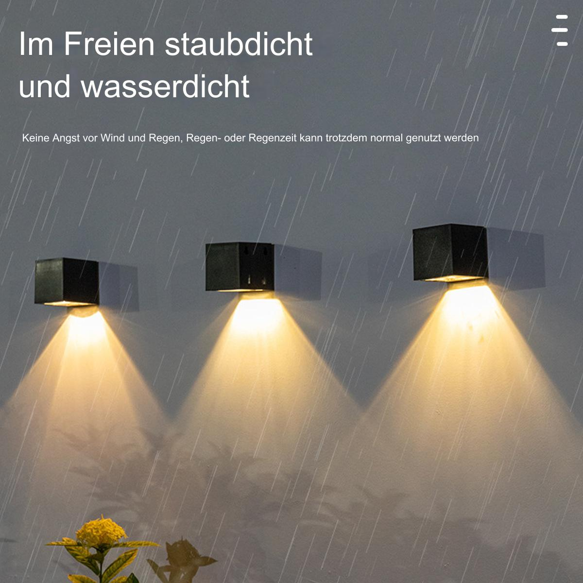 Drei schwarze Außenwandleuchten mit gelbem Strahl nach unten, mit Regen-Effekt.