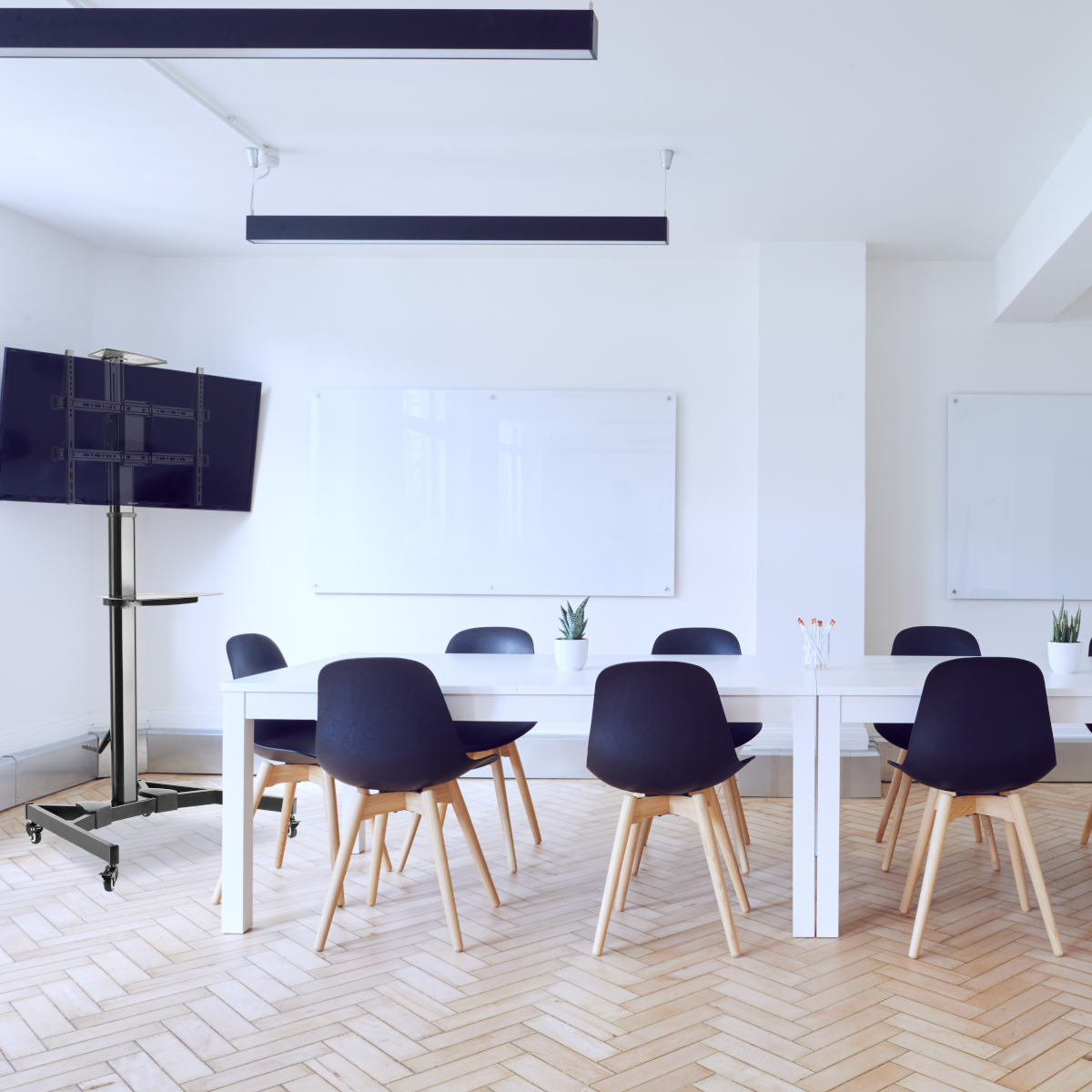 Konferenzraum: TV auf Ständer, Whiteboards, Tisch, Stühle. Heller, moderner Büroraum.