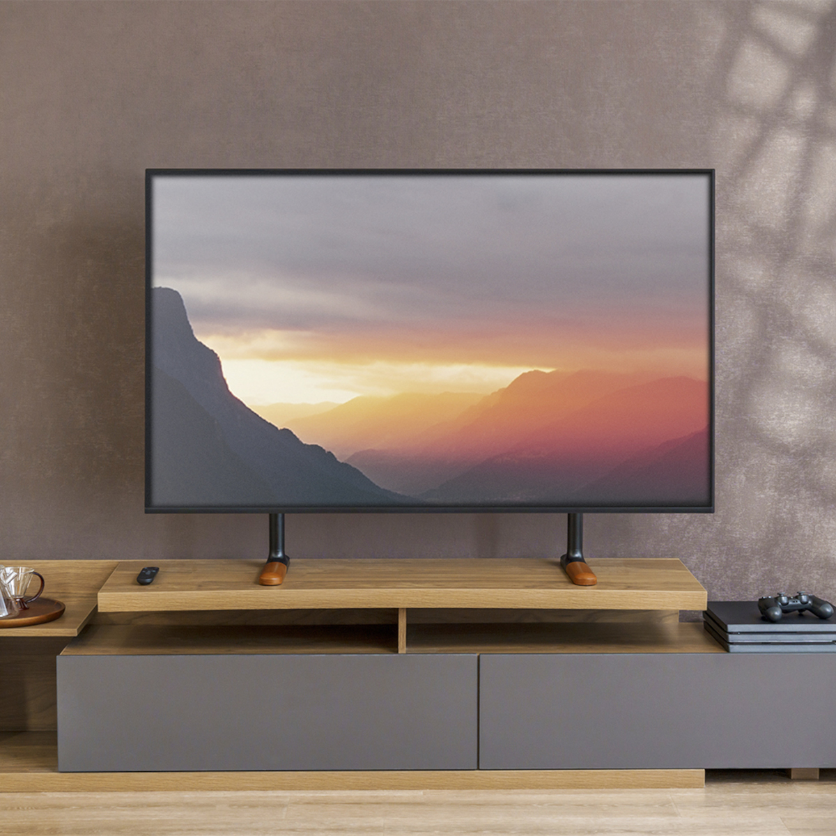 Fernseher auf einem Holzständer, der einen Sonnenuntergang zeigt. Braune Wand im Hintergrund, darunter eine Konsole.