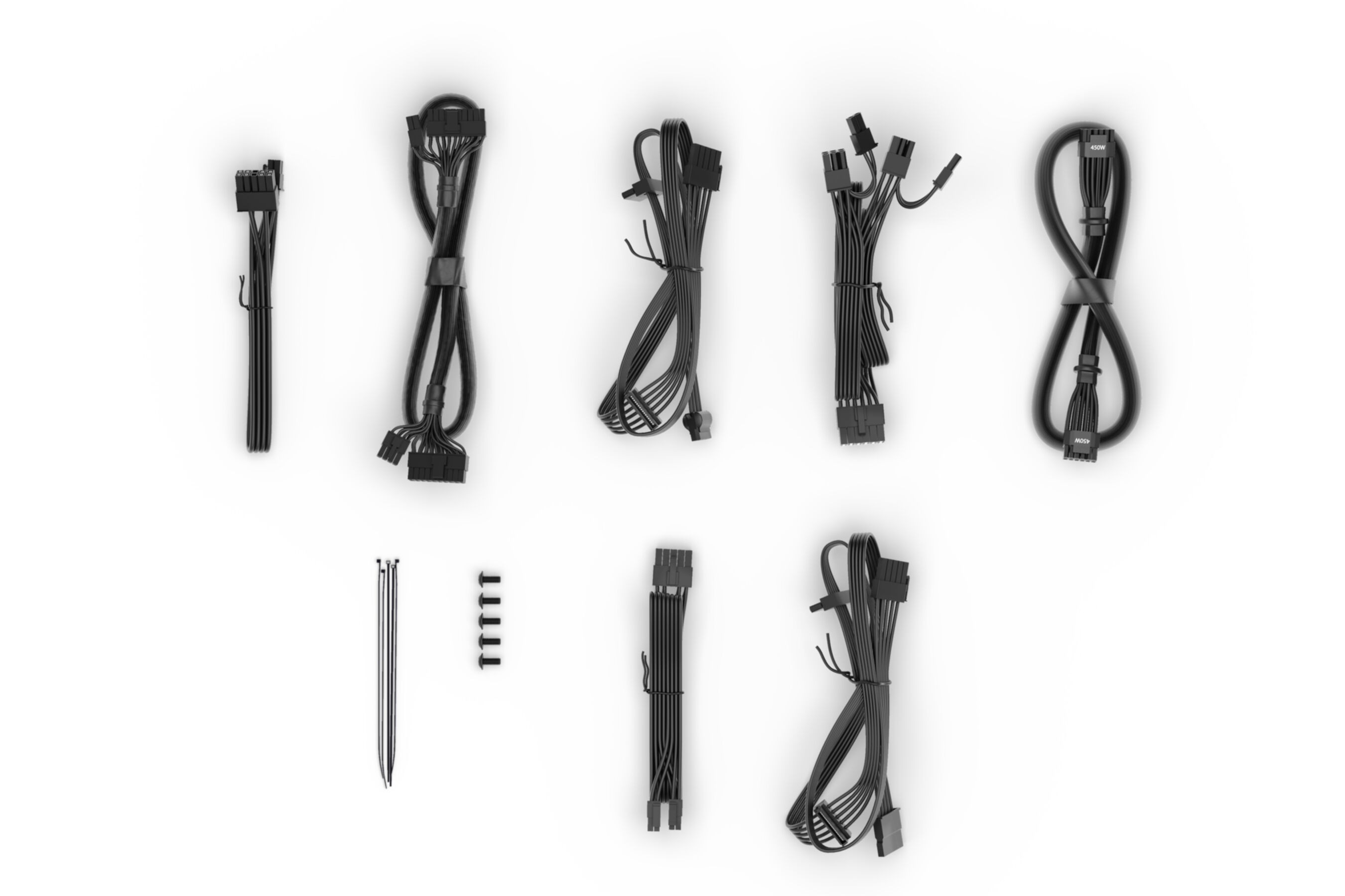 Cables y conectores de alimentación negros variados, dispuestos sobre una superficie blanca.