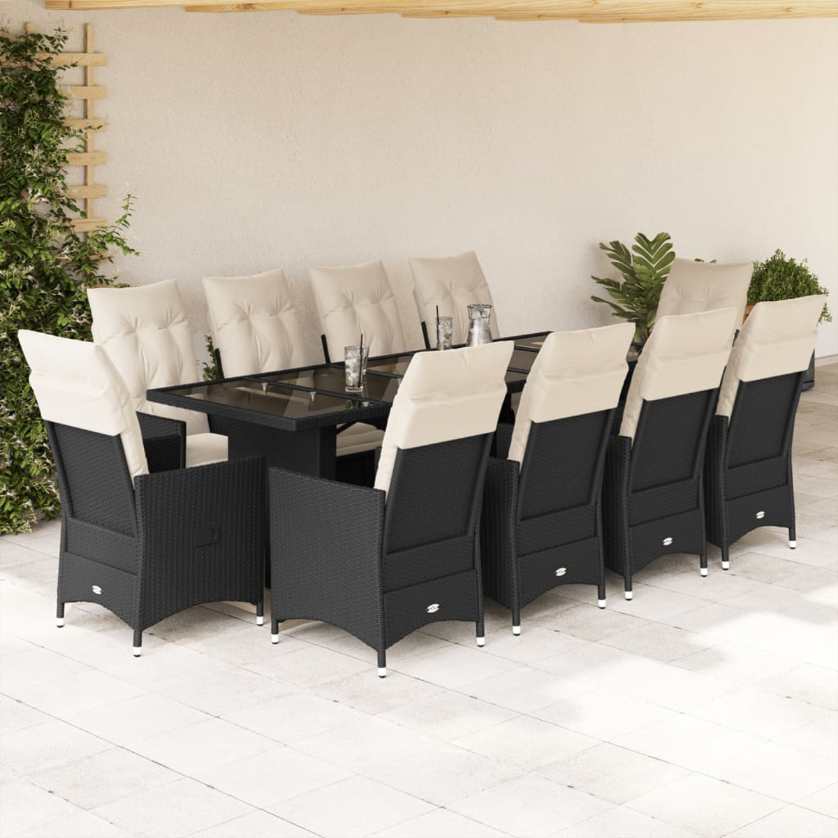 Terrassenset mit schwarzen Rattan-Stühlen, cremefarbenen Kissen und einem dunklen Tisch unter einem weißen Dach.