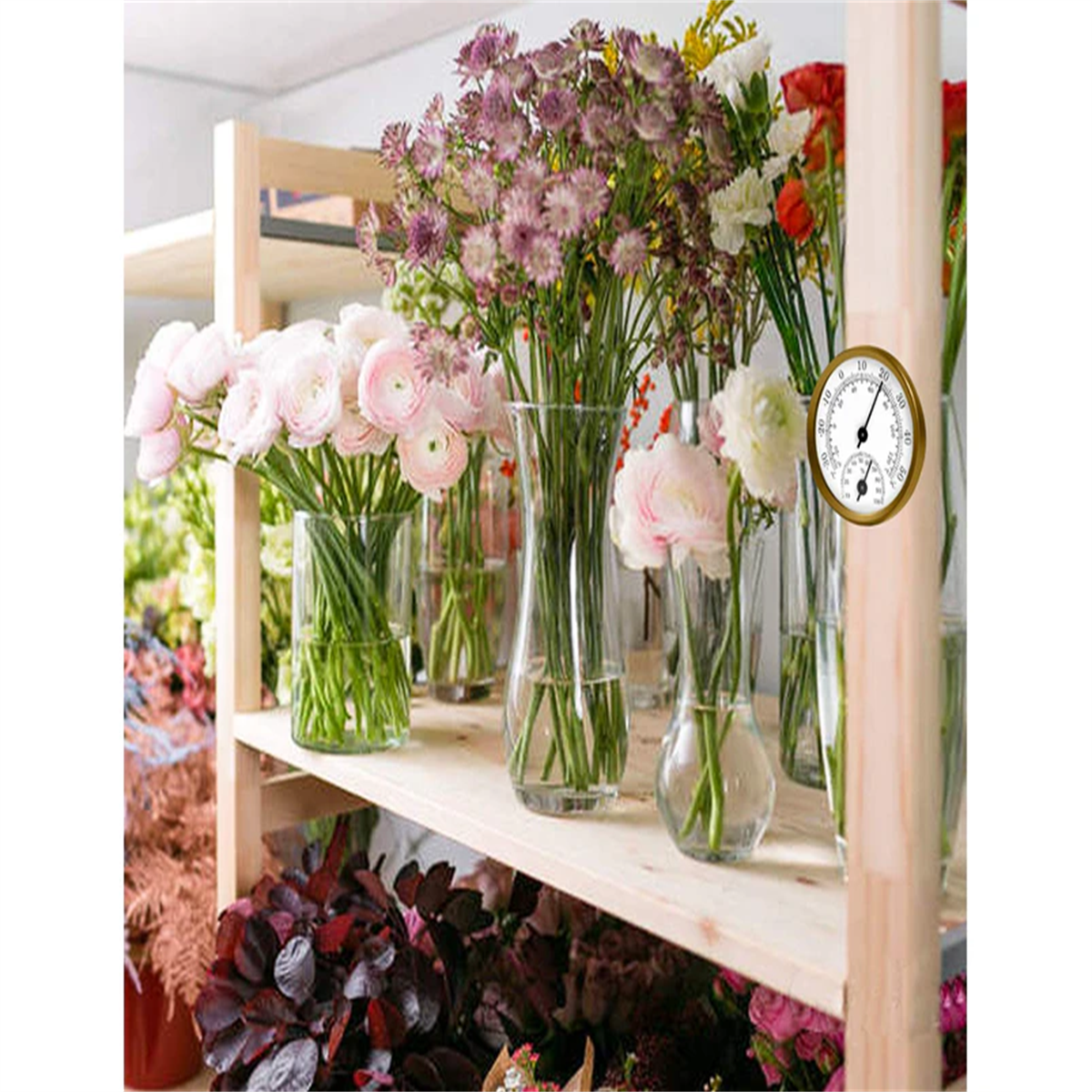 Ein Blumengeschäft mit Vasen mit Blumen auf Regalen. Rechts ist ein Thermometer.