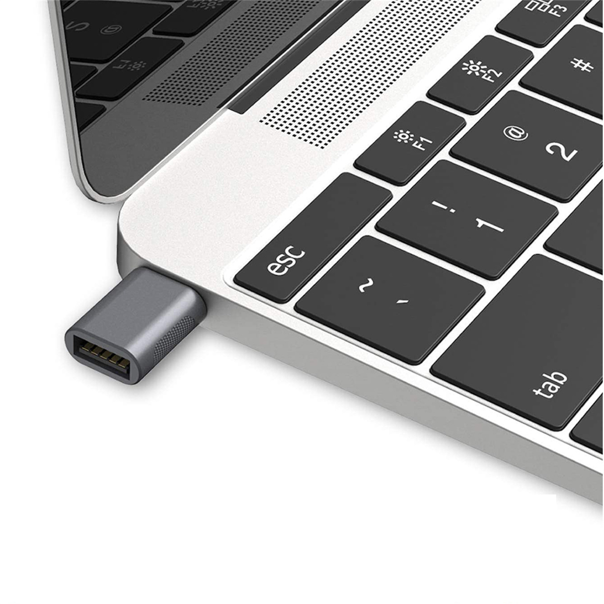 Nahaufnahme eines silbernen USB-C-Adapters, der an einen Laptop angeschlossen ist. Schwarze Tasten mit weißen Buchstaben sind sichtbar.