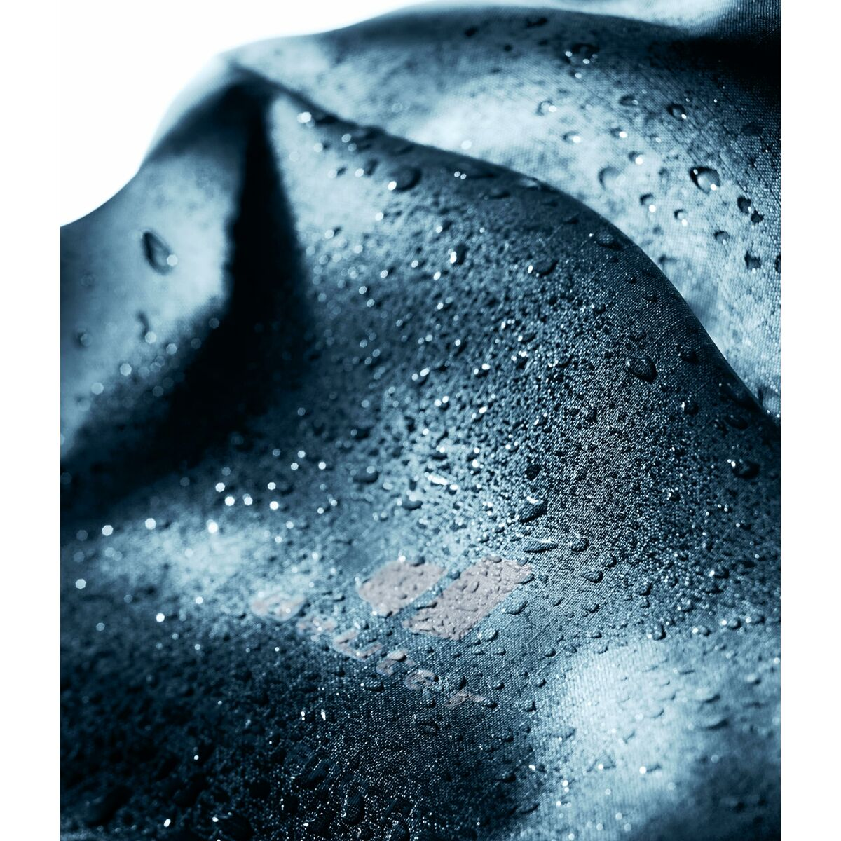 Nahaufnahme eines marineblauen, wasserabweisenden Stoffes mit Wassertropfen.