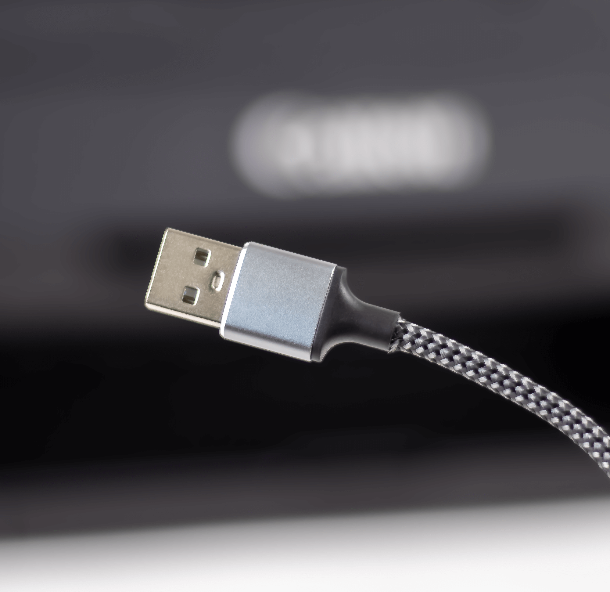 Kabel USB ze srebrną wtyczką i czarno-szarym plecionym kablem.