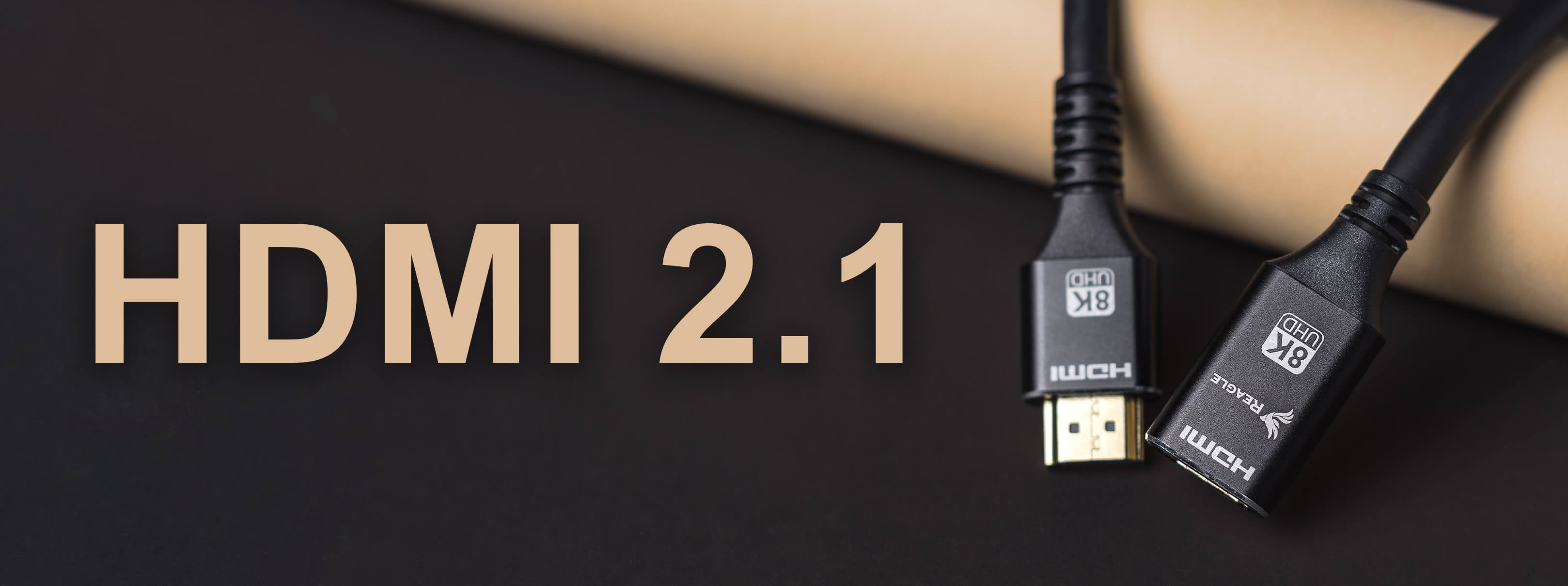 Dwa czarne kable HDMI 2.1 ze złotymi złączami, na teksturowanej ciemnej powierzchni.