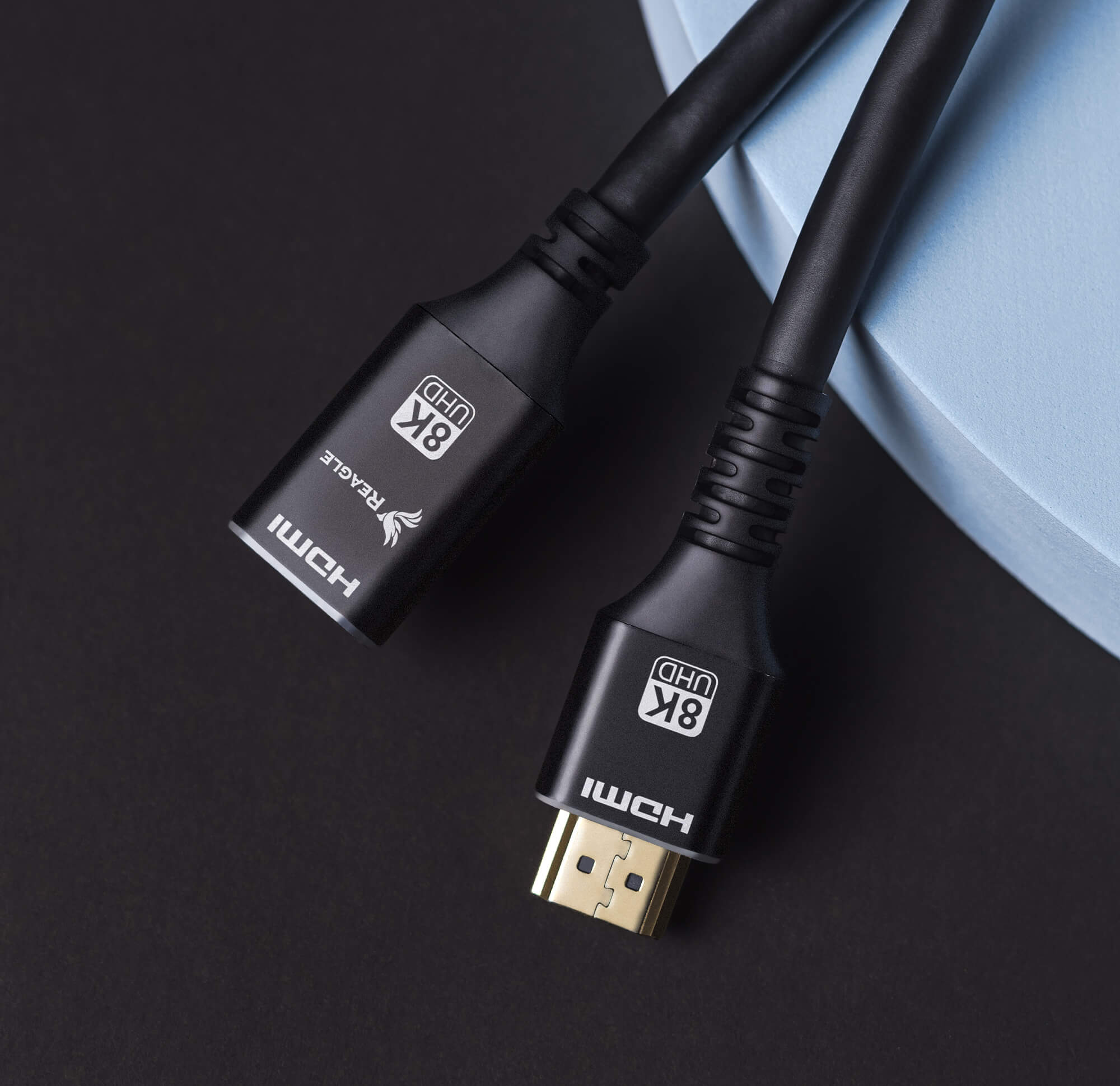 Dwa czarne kable HDMI ze złotymi złączami, oznaczone '8K UHD', na ciemnej powierzchni.