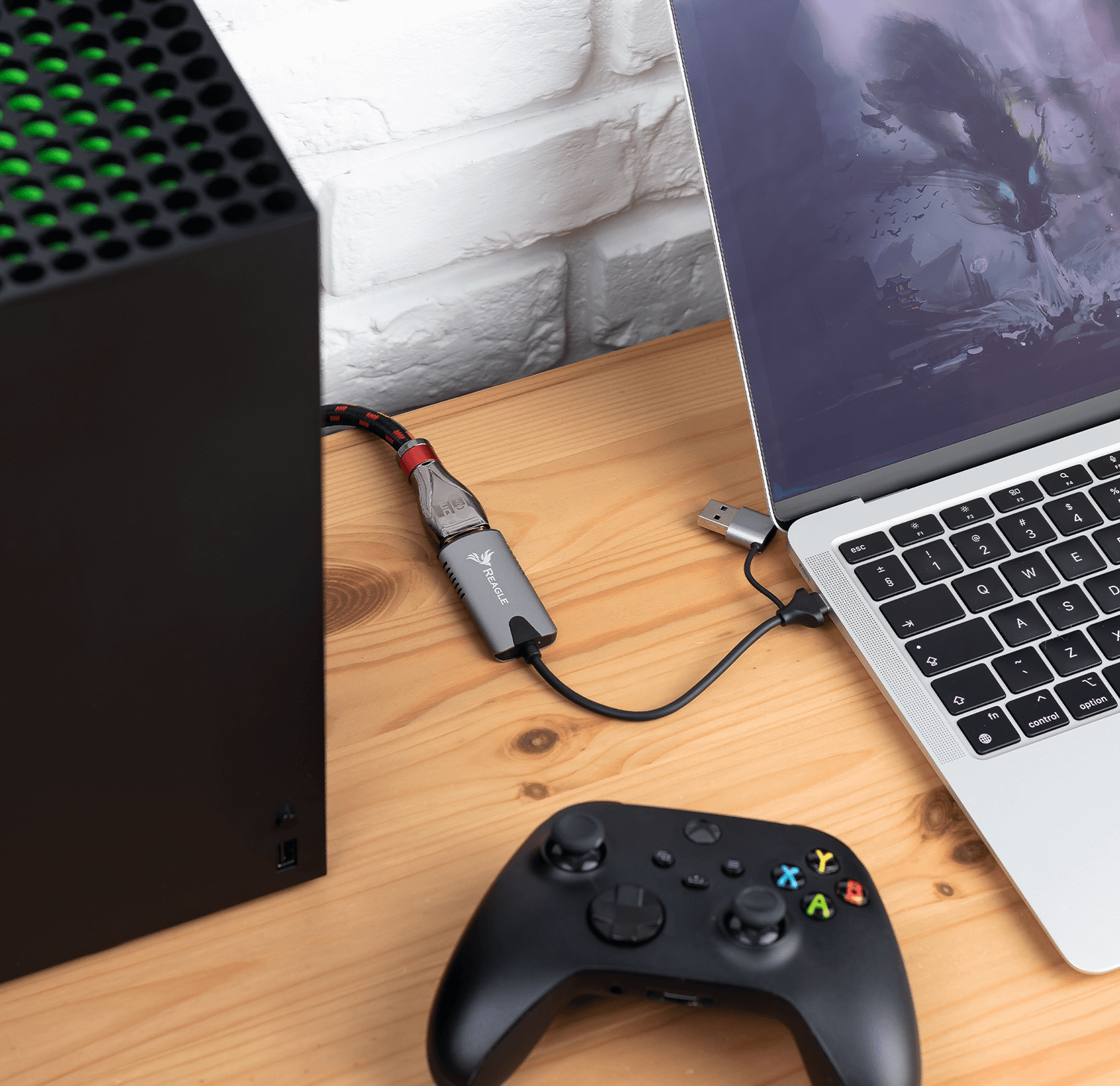 Czarny Xbox Series X podłączony do laptopa kablem USB i kontrolerem na drewnianym stole.