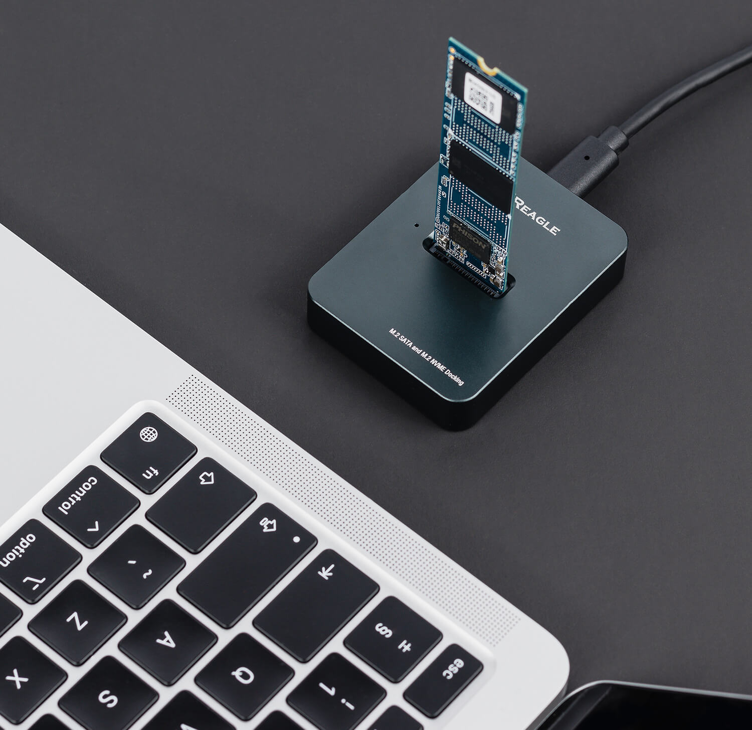 Eine schwarze Dockingstation mit einer blauen SSD und einer Laptop-Tastatur auf schwarzem Hintergrund.