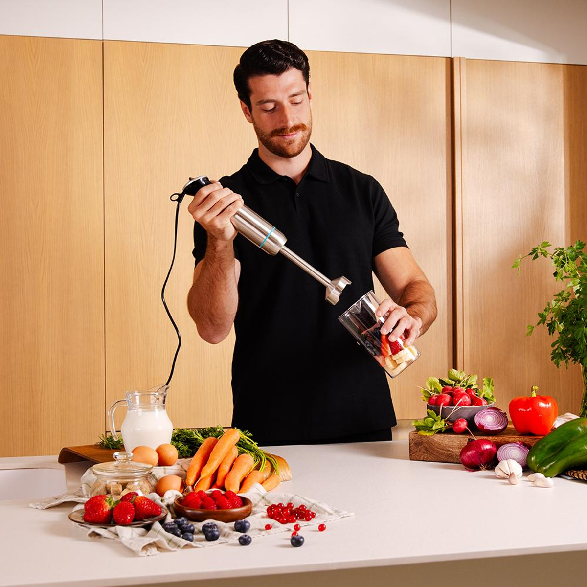 Uomo che usa un frullatore con frutta, uova e verdure.