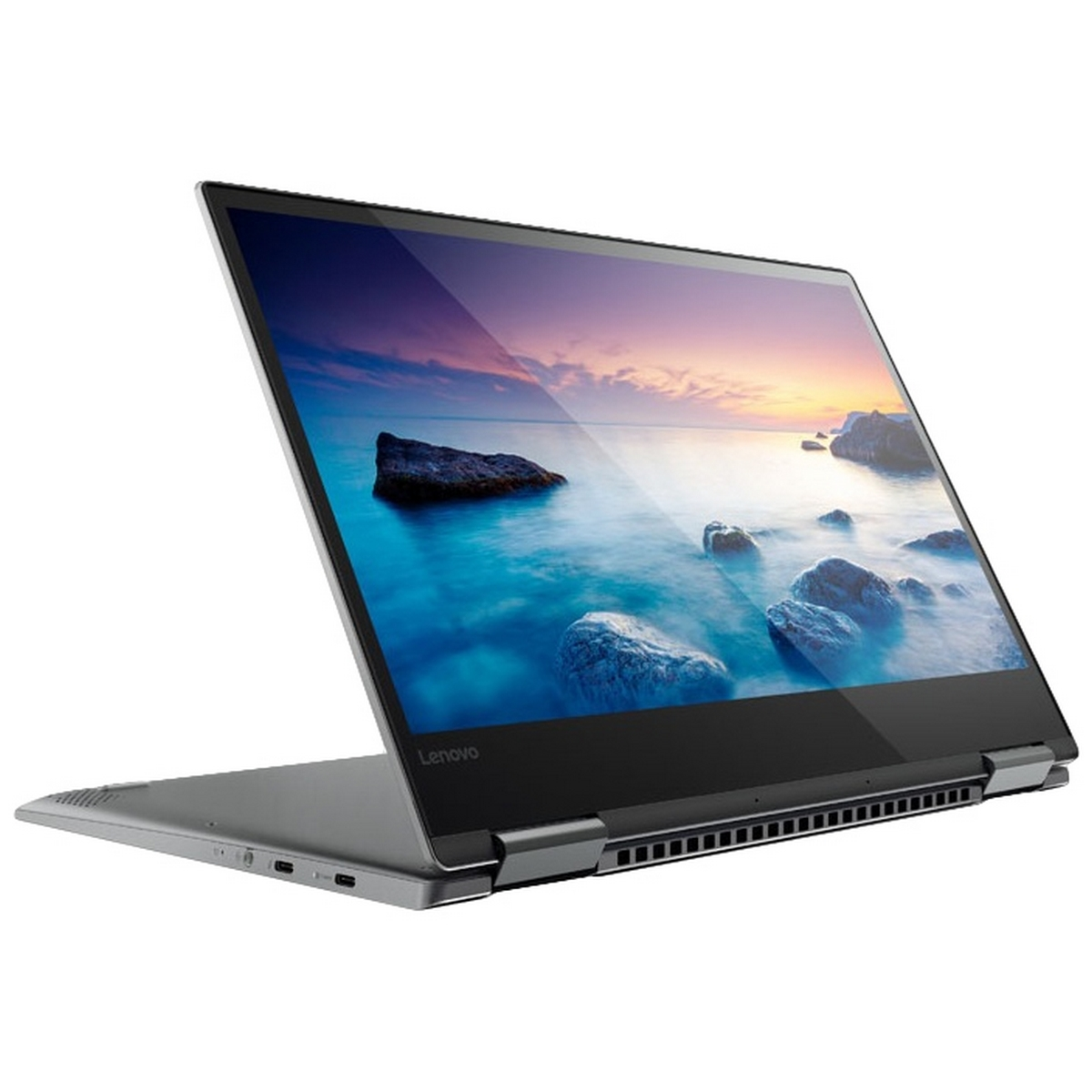 Un laptop Lenovo argentato è aperto, mostra un paesaggio marino, con costa rocciosa e tramonto.