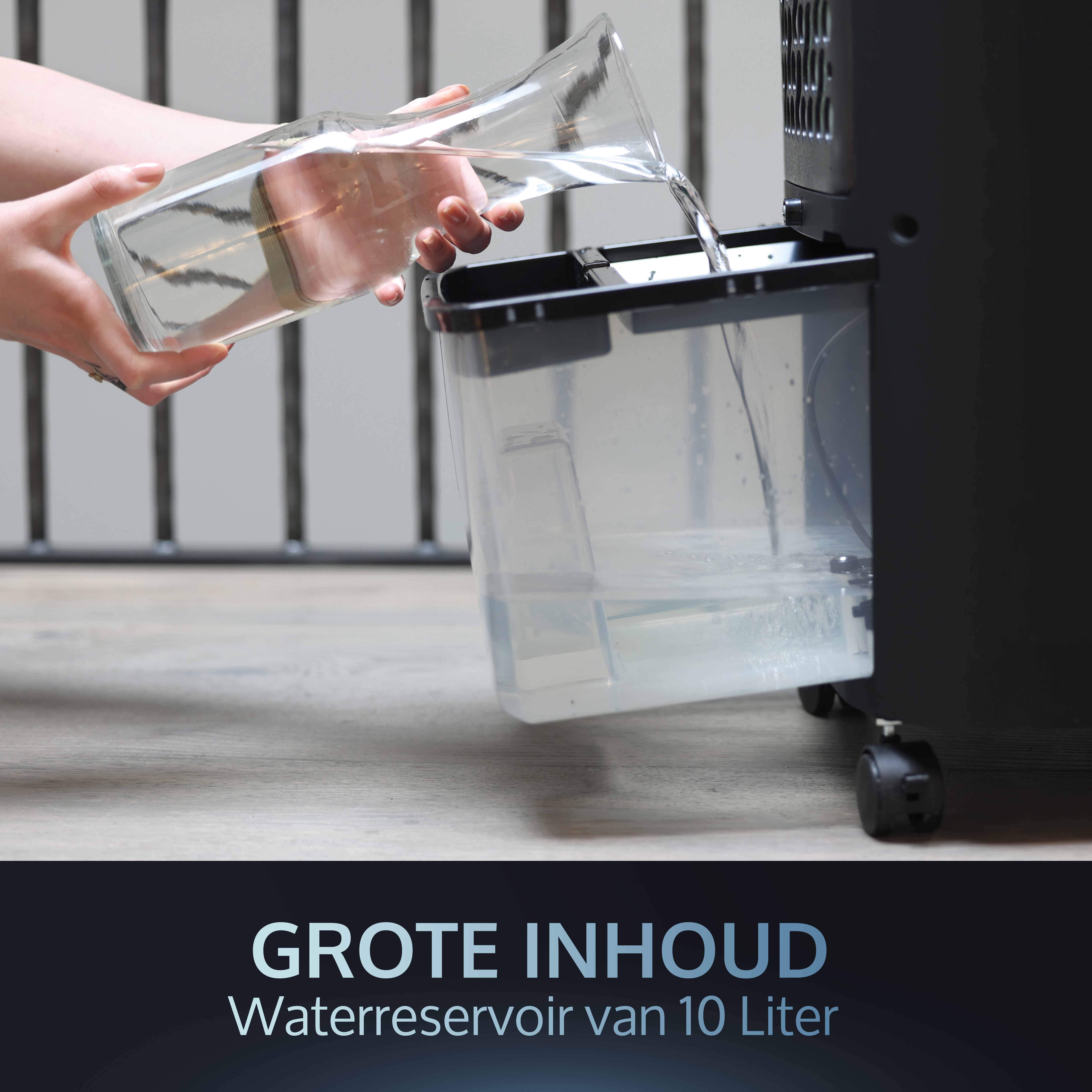 Eine Person gießt Wasser aus einem Krug in den Wasserbehälter eines schwarzen Luftkühlers, der mit Text beschriftet ist.