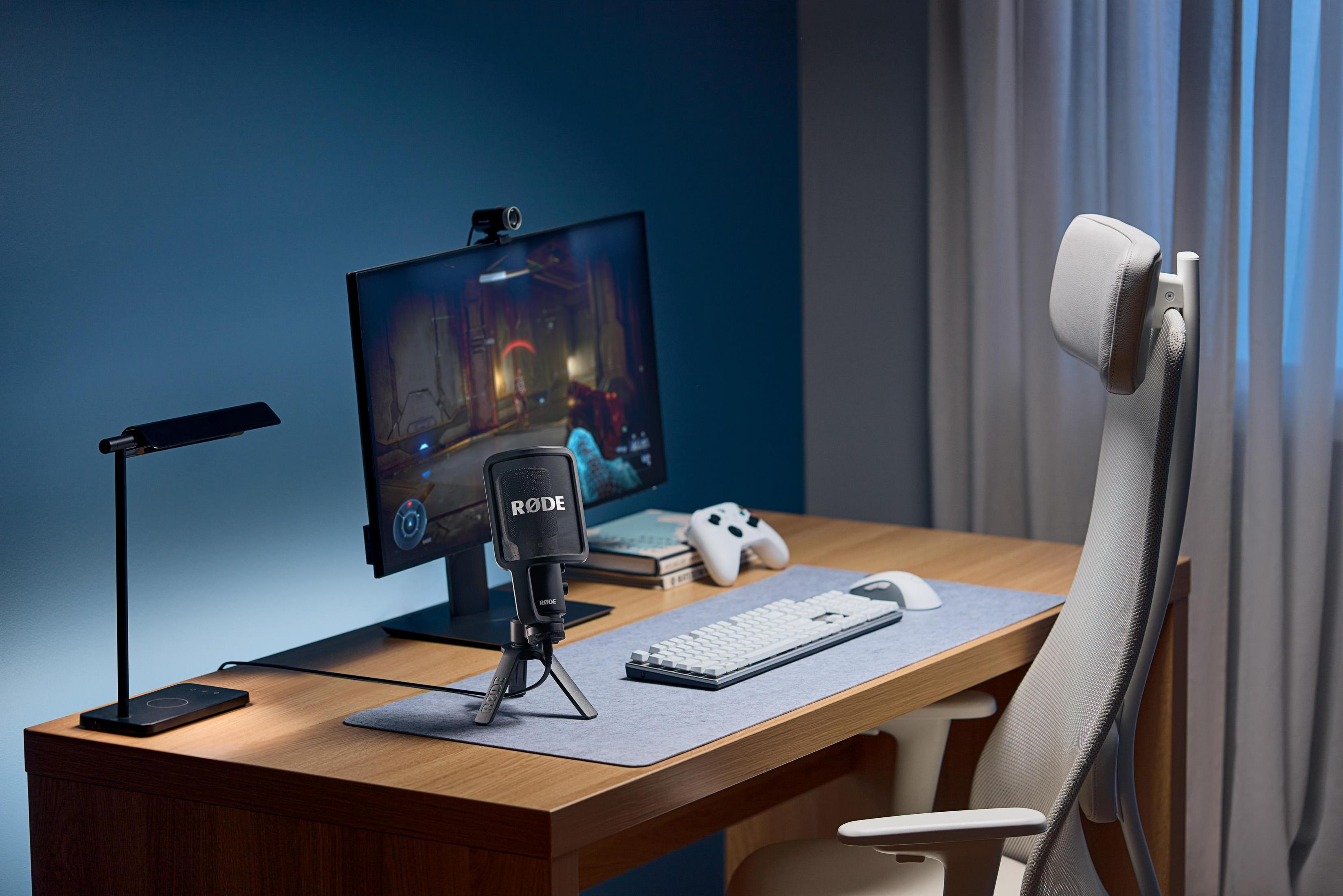 Konfiguracja biurka z monitorem komputerowym, mikrofonem i klawiaturą. Kontroler do gier jest na biurku.