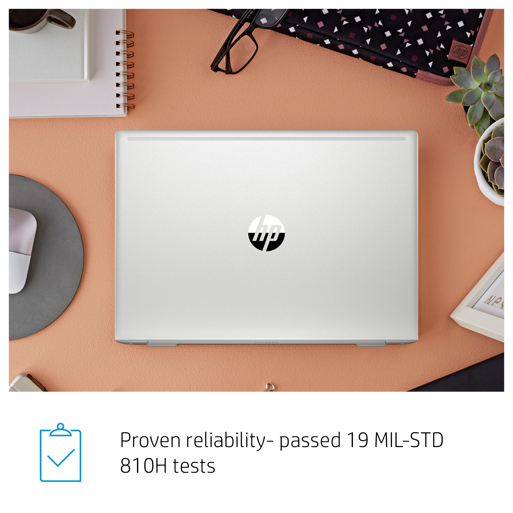 Laptop con logo HP sul coperchio, circondato da forniture per ufficio su una superficie color pesca.