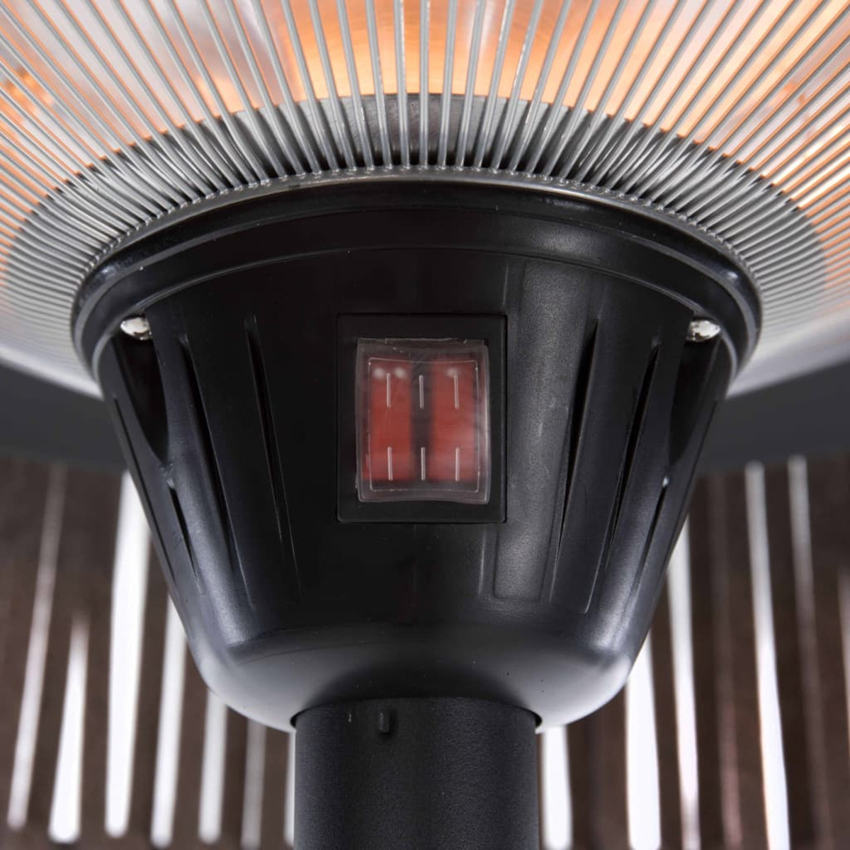 Close-up van een zwarte terrasverwarmer. Kenmerken zijn een rode schakelaar en een metalen rooster.