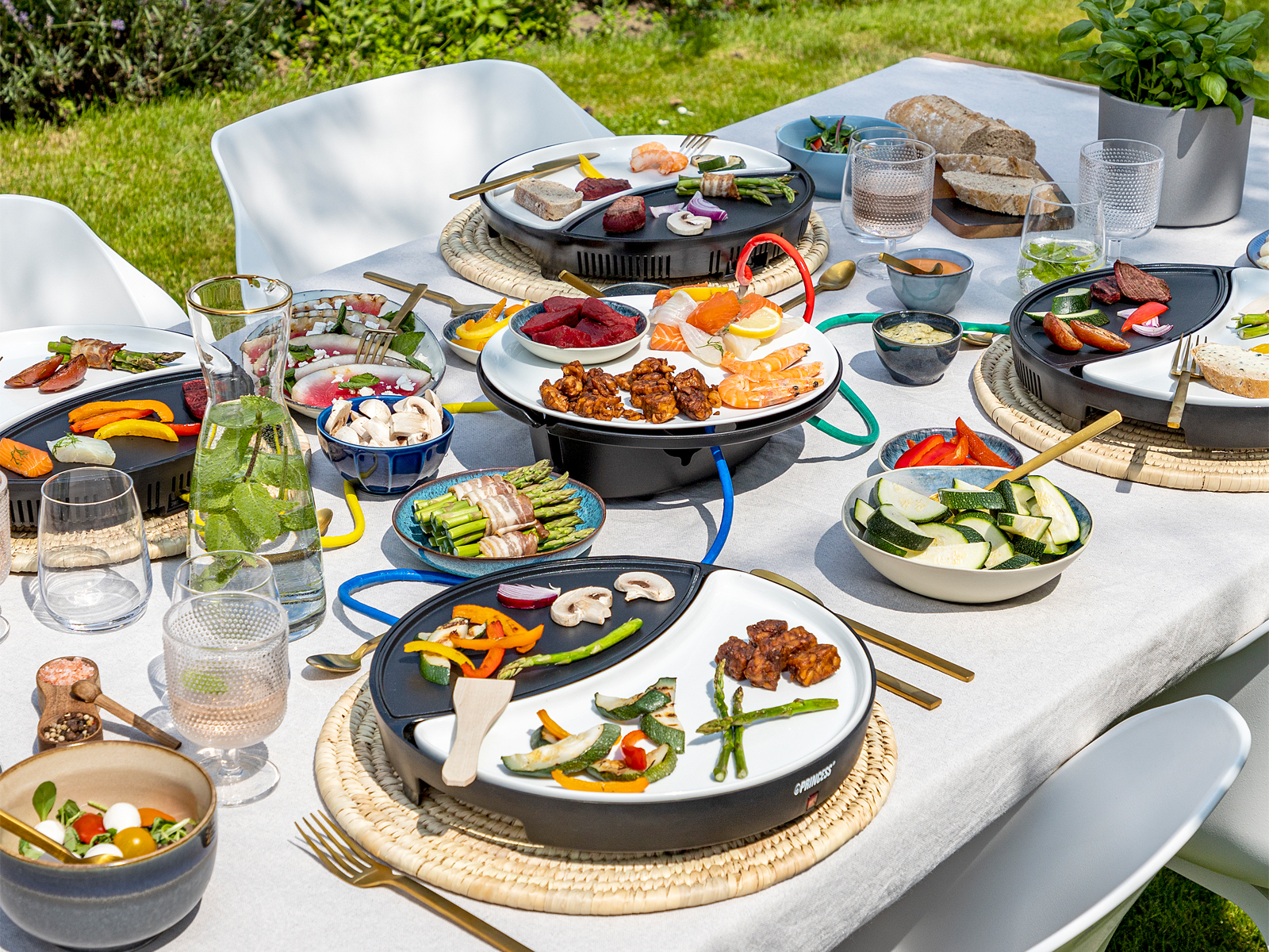 Nakrycie stołu do posiłku z talerzami z jedzeniem, szklankami i elementami dekoracyjnymi.