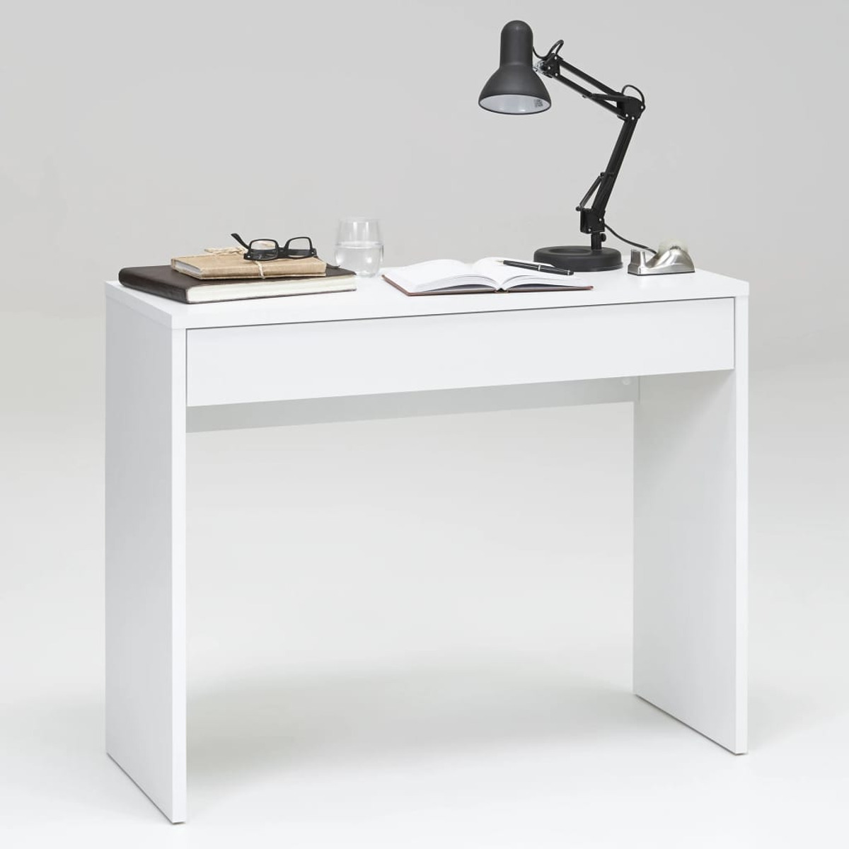 Weißer Schreibtisch mit Büchern, Brille, Lampe, Wasserglas und Stift. Sauberes, helles, modernes Setup.