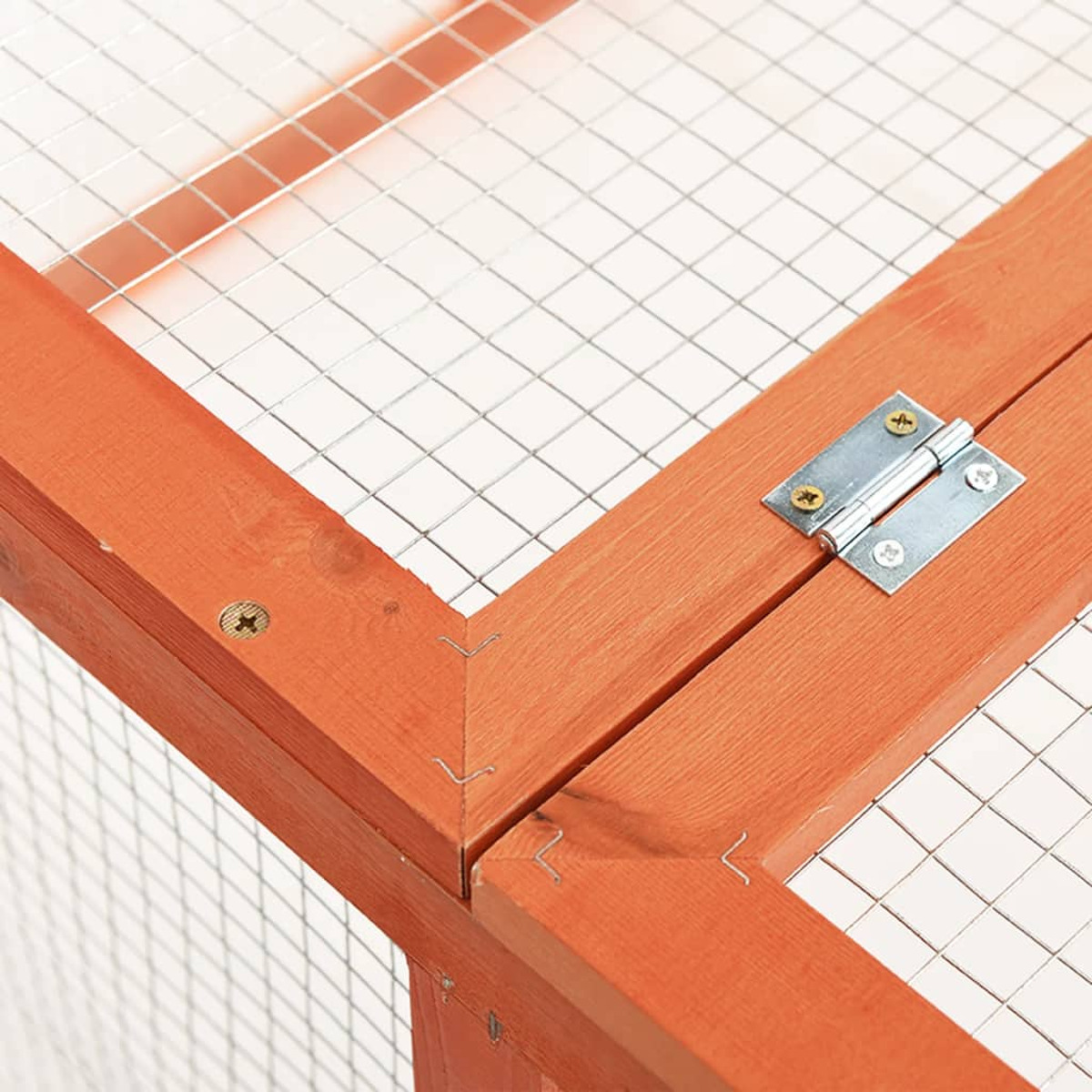 Nahaufnahme eines Holzrahmens mit Drahtgeflecht. Der Rahmen ist orange, mit einem Metallscharnier und Schrauben.