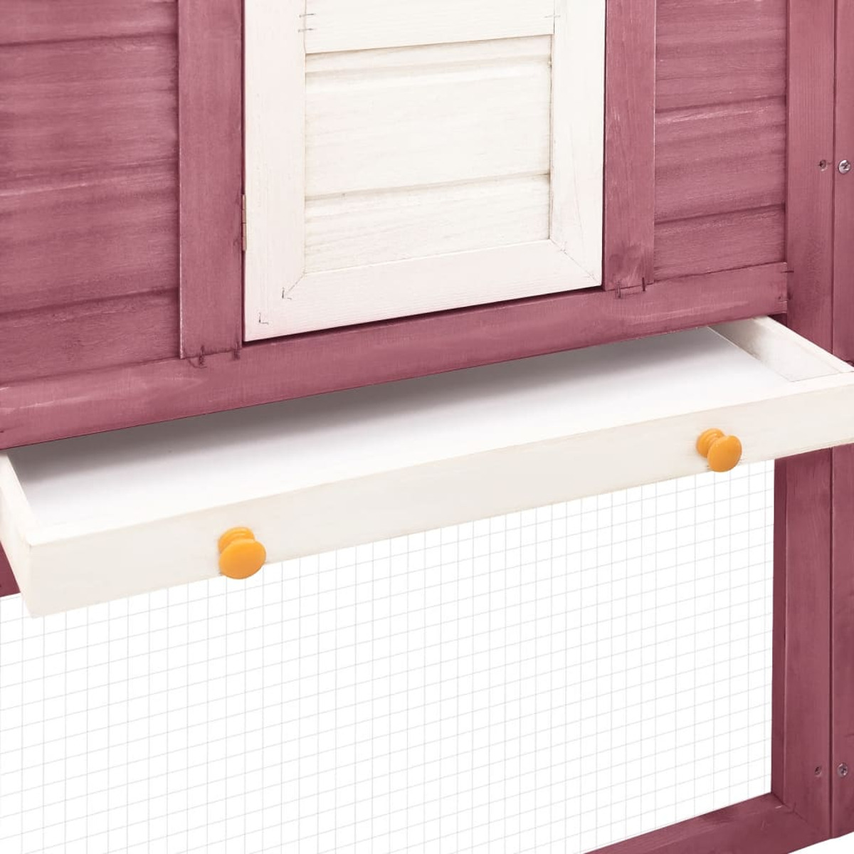Schublade eines Hühnerstalls mit weißer Ablage und orangefarbenen Knöpfen.