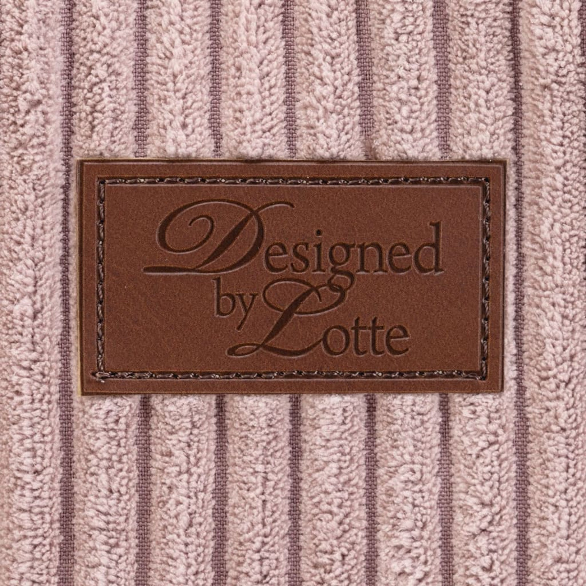 Nahaufnahme eines braunen Etiketts auf einem Handtuch. Der Text lautet 'Designed by Lotte'.