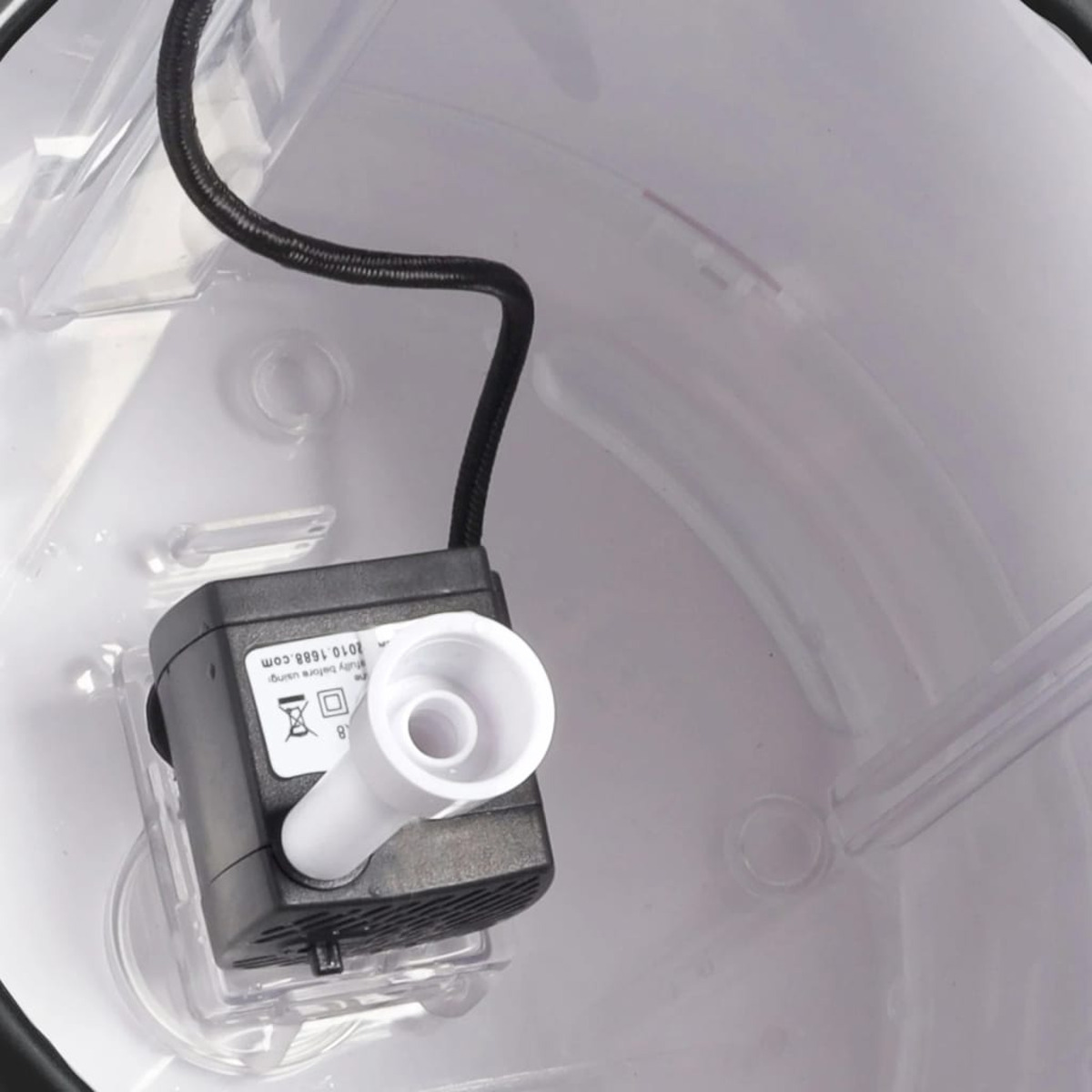 Kleine, schwarze Wasserpumpe in einem weißen Behälter. Schwarzes Kabel und weiße Düse.
