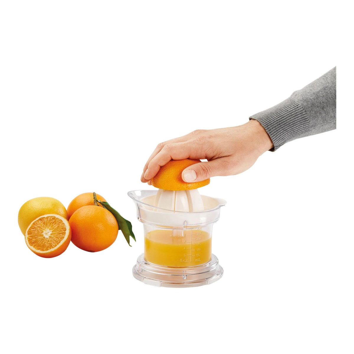 Persona exprimiendo naranja en exprimidor. Naranjas, algunas cortadas, cerca.