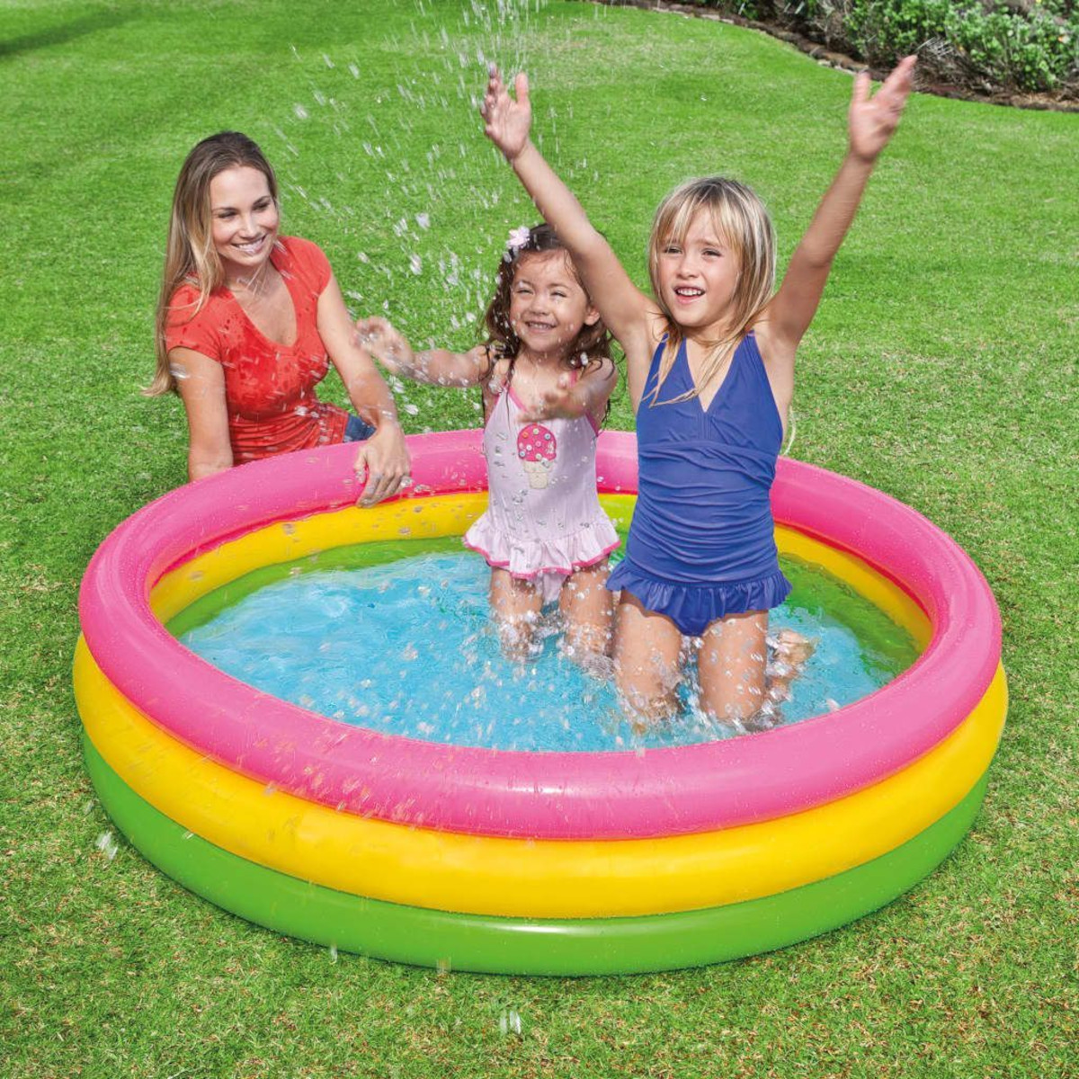 Drei Personen in einem Pool. Zwei Kinder planschen, ein Erwachsener schaut zu.