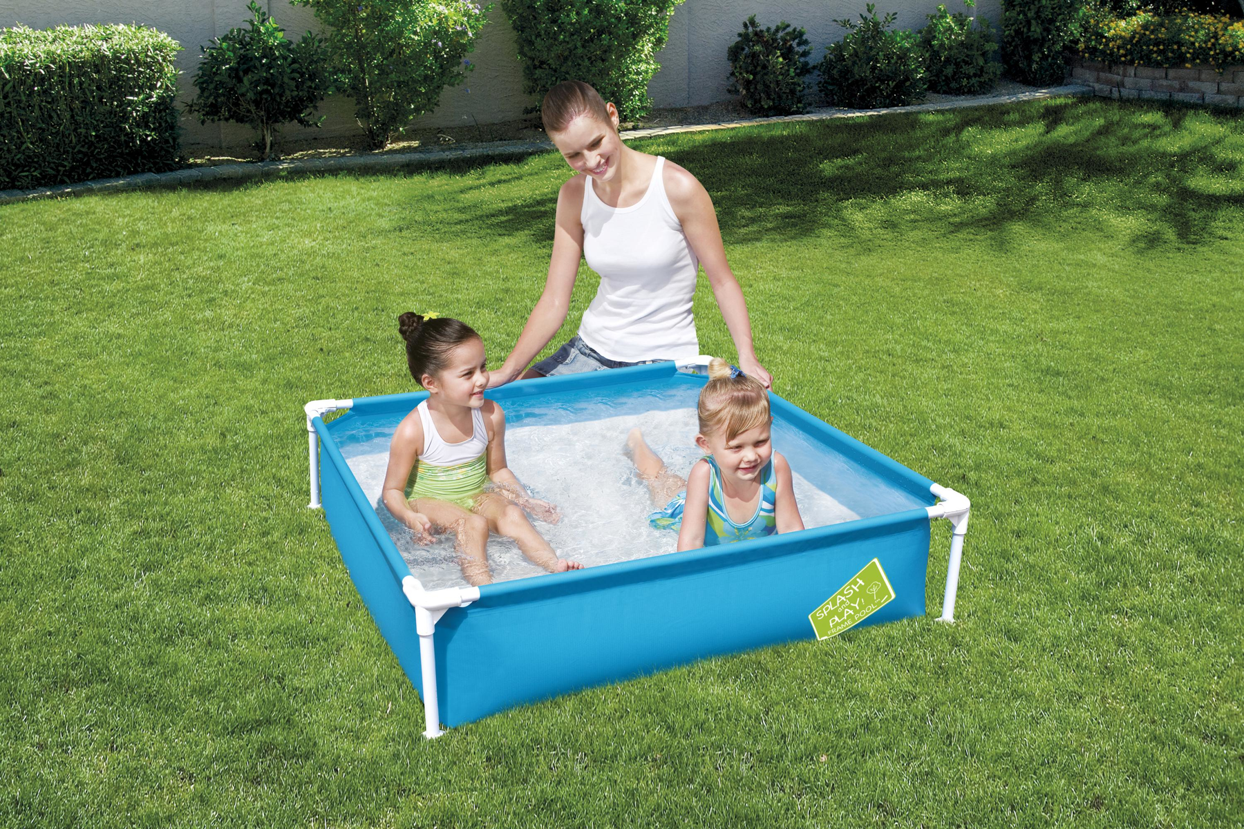 Eine Frau beobachtet zwei kleine Kinder, die in einem kleinen blauen Pool spielen.