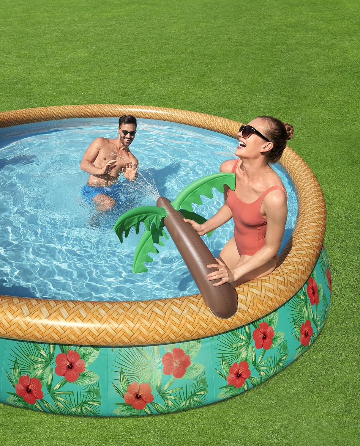 Leute in einem Pool mit einem Palmen-Schwimmer. Grünes Gras und Poolhintergrund.