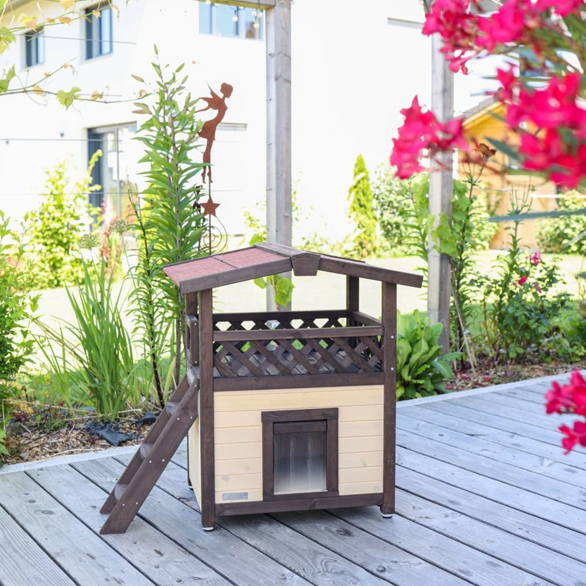 Casa de perro de madera con escalera y figura de metal decorativa.