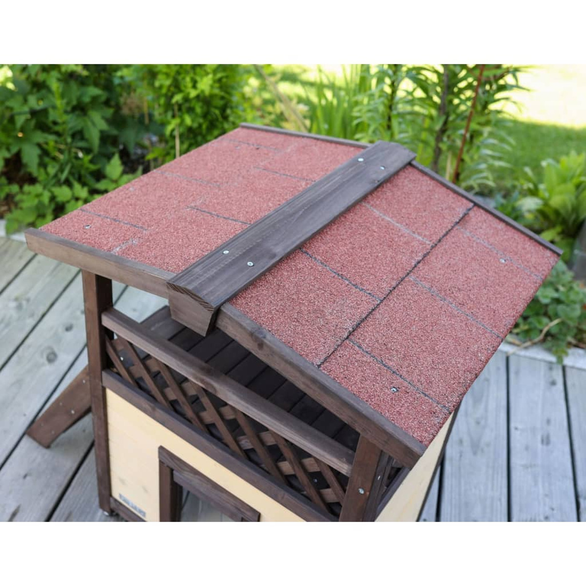 Una caseta para perros pequeña con techo rojo. Está hecha de madera.