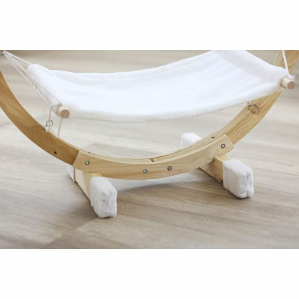 Hamaca para gatos de madera. Cama blanca y esponjosa suspendida en un marco de madera curvado.