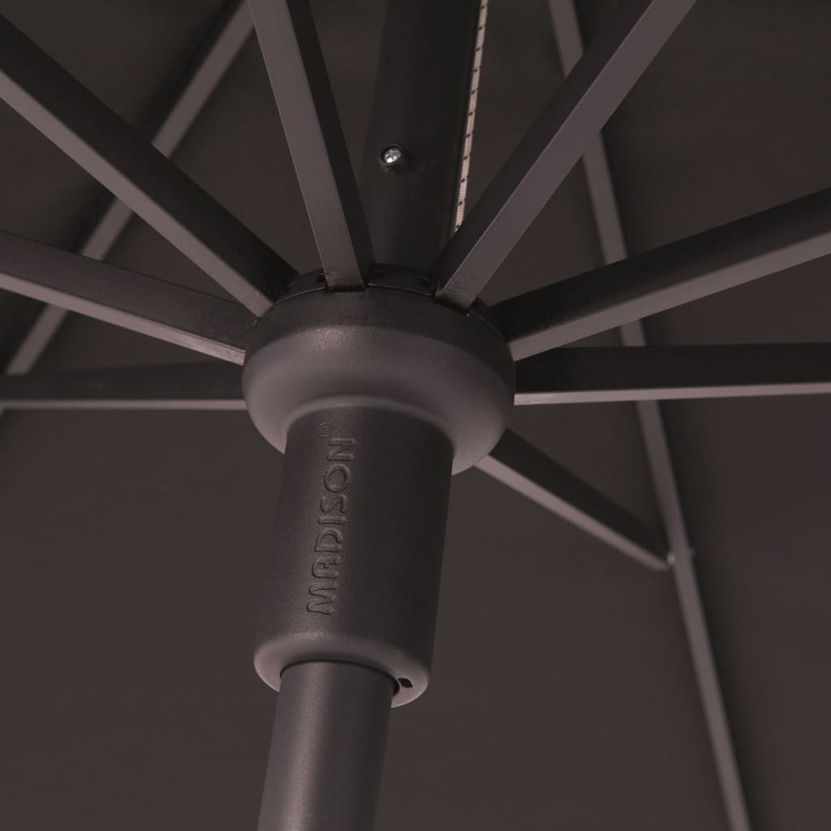 Close-up of black umbrella center. Branding on pole. Dark background.
