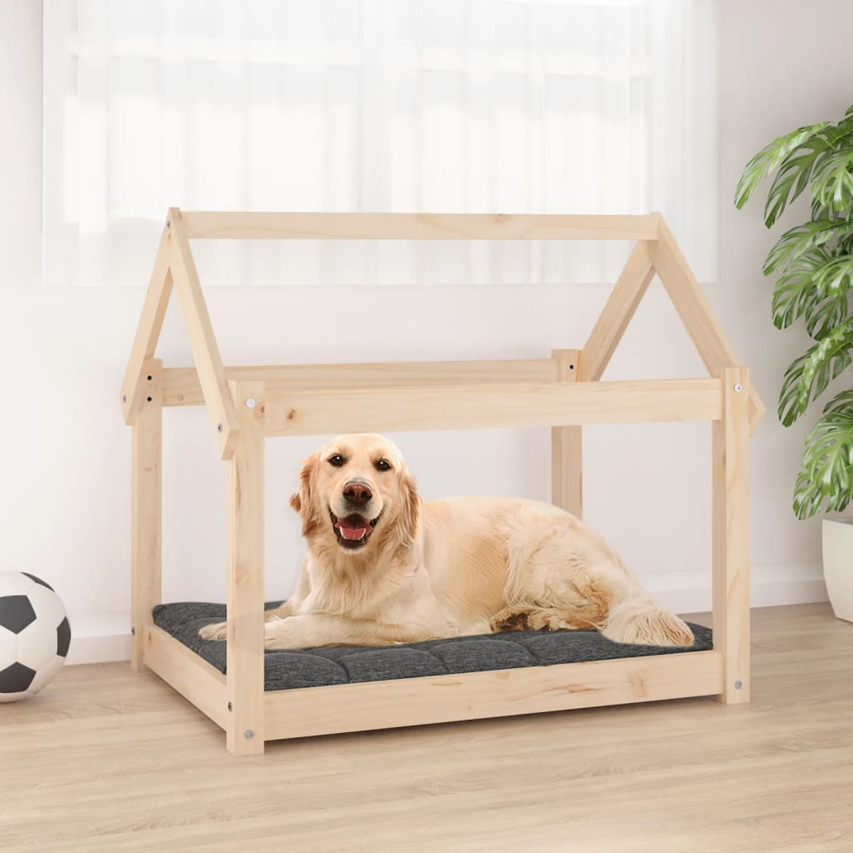 Hund in einem Holzbett mit grauem Kissen auf einem Hartholzboden.