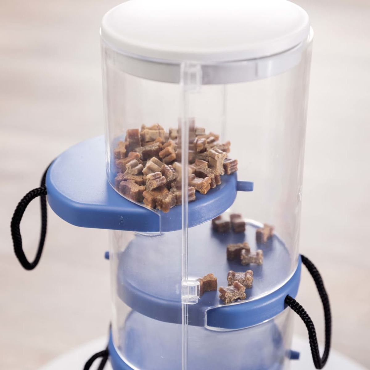 Un dispensador de golosinas para mascotas con golosinas dentro. Transparente y azul.