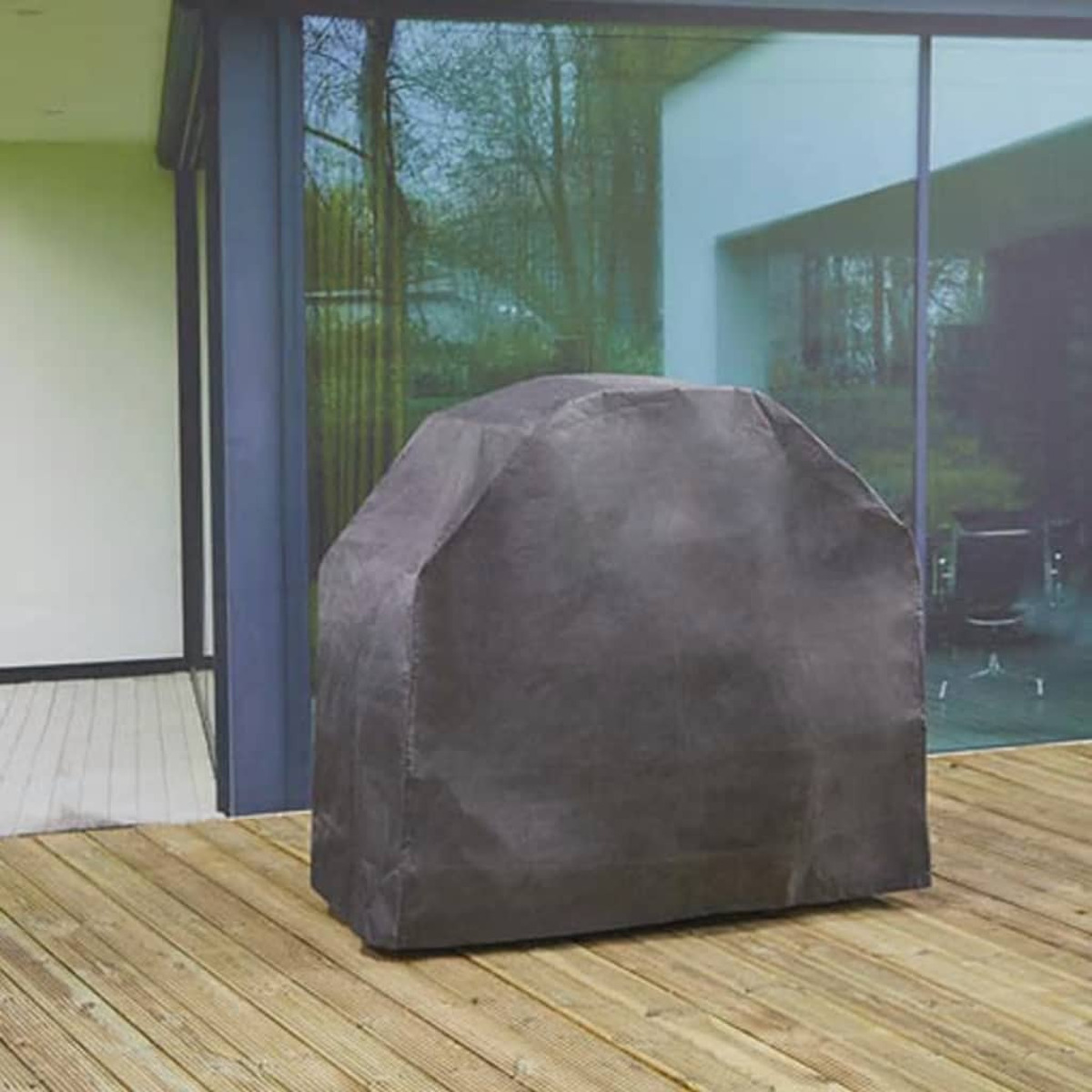 Copertura griglia grigio scuro su decking in legno. Alberi e parete di vetro sullo sfondo.