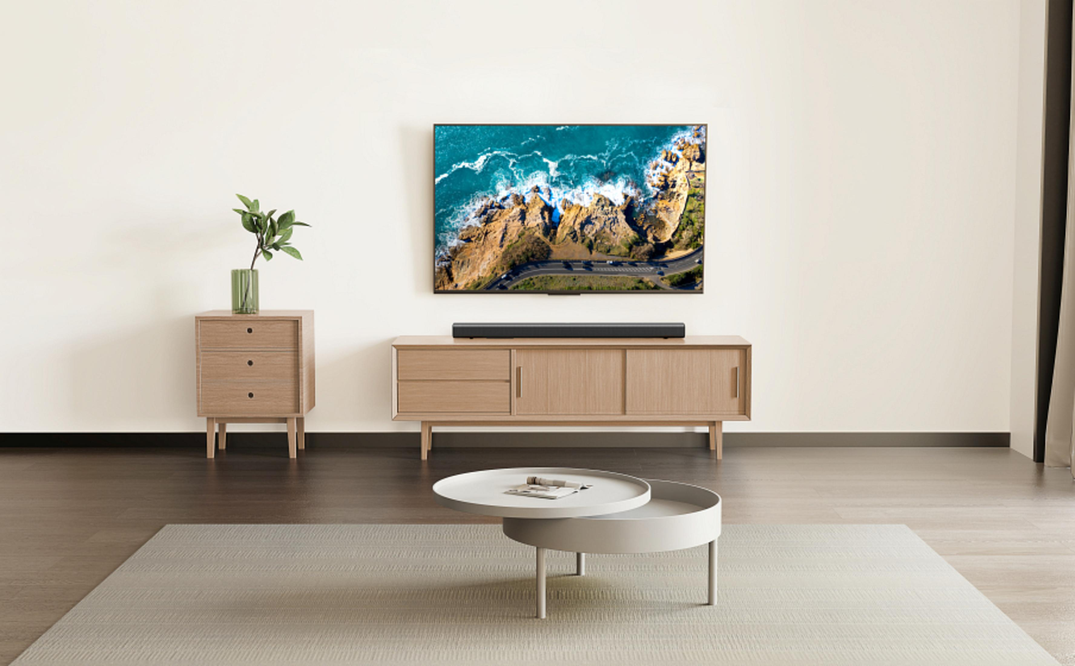 Salon z telewizorem nad drewnianą szafką. Obecny jest mały stolik i szafka boczna z rośliną.