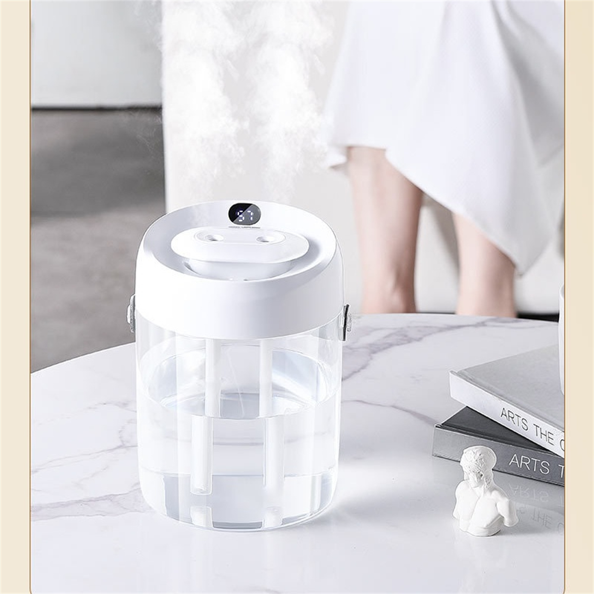 Weißer Luftbefeuchter mit Wassertank und Digitalanzeige. Er steht auf einem Tisch.