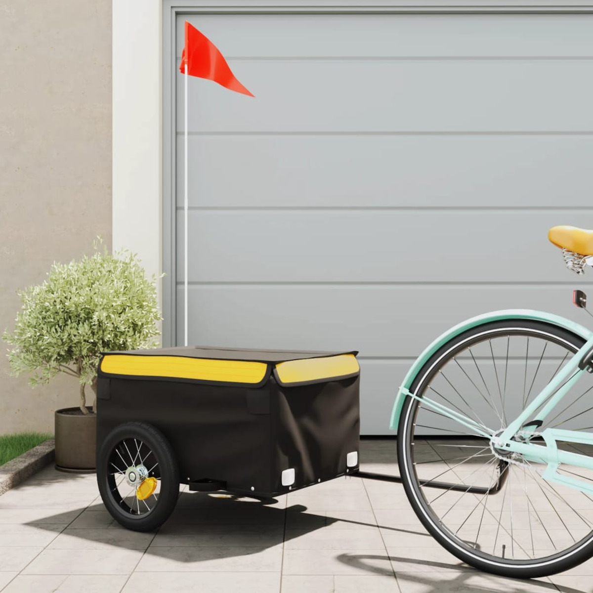 Schwarzer und gelber Anhänger an einem hellblauen Fahrrad. Eine rote Fahne ist an der Garage befestigt.