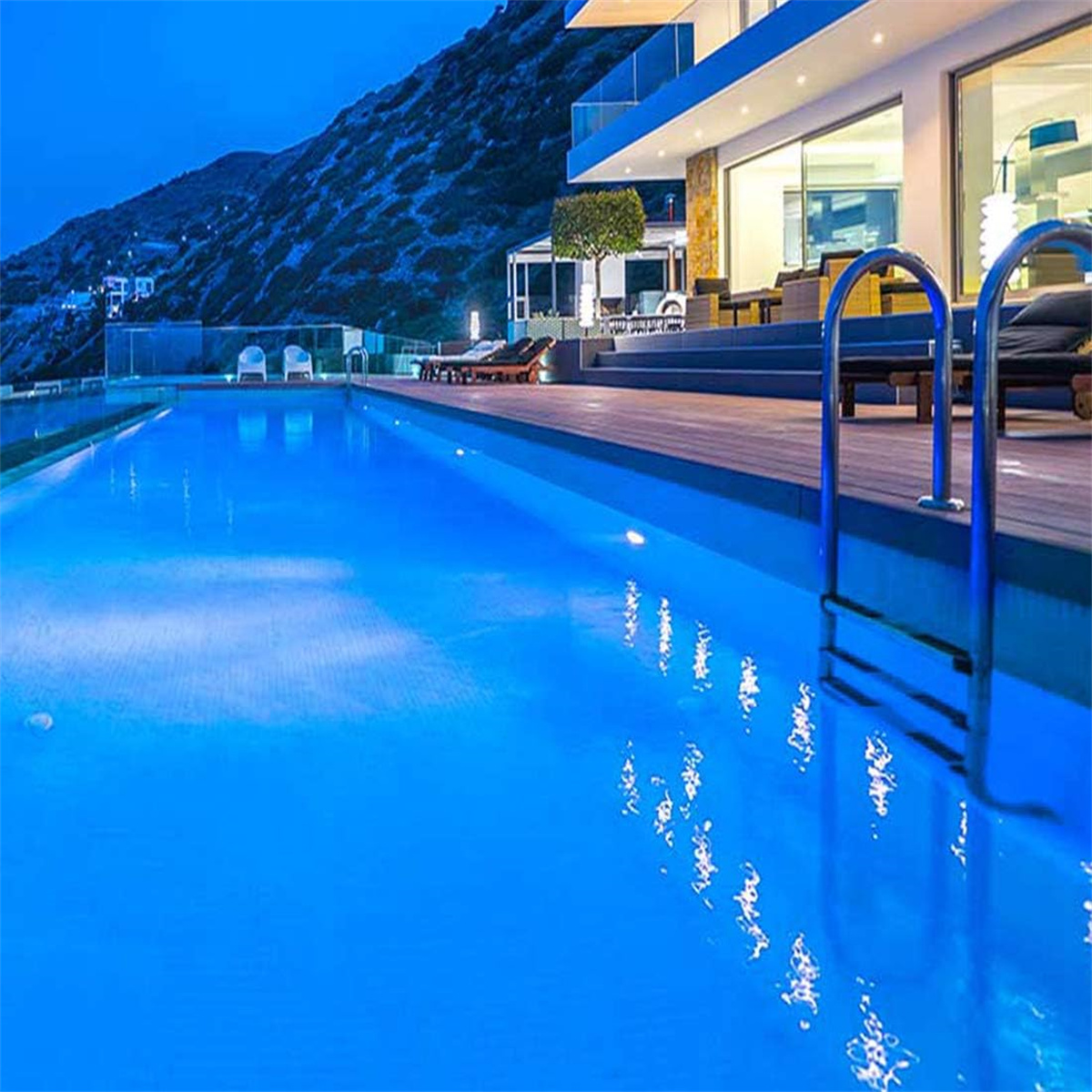 Pool bei Nacht mit Haus und Berg im Hintergrund.